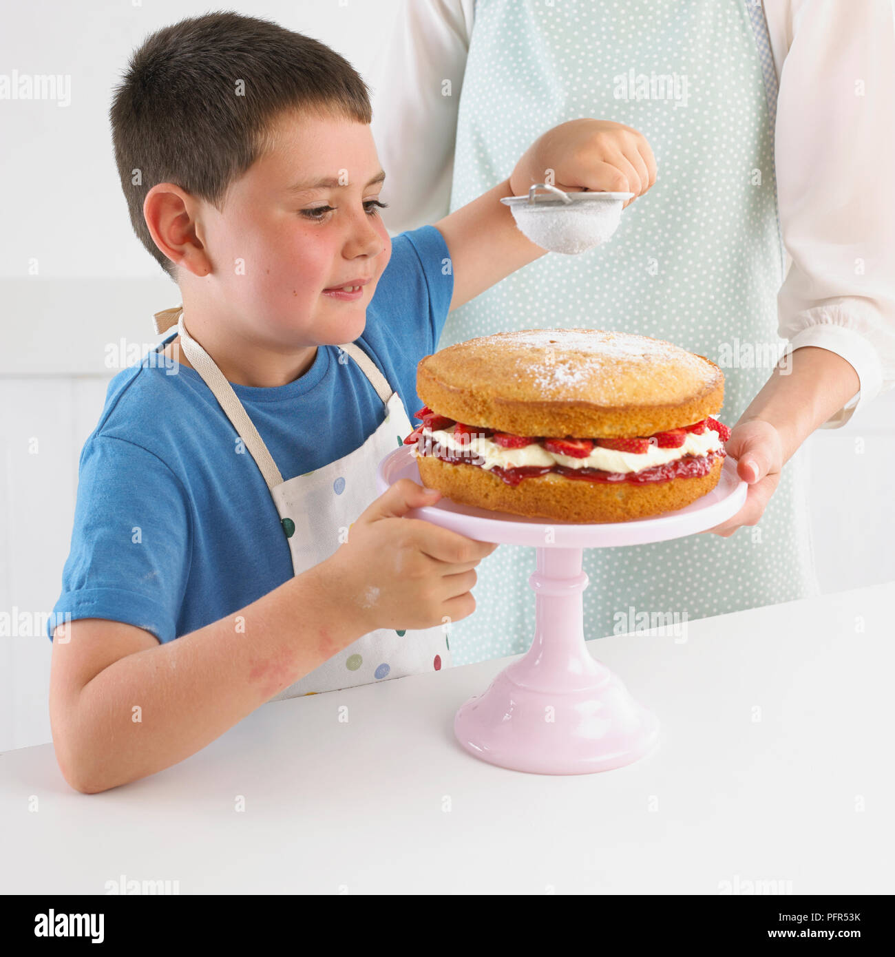 Tamisage garçon sucre à glacer gâteau aux fraises, 7 ans Banque D'Images
