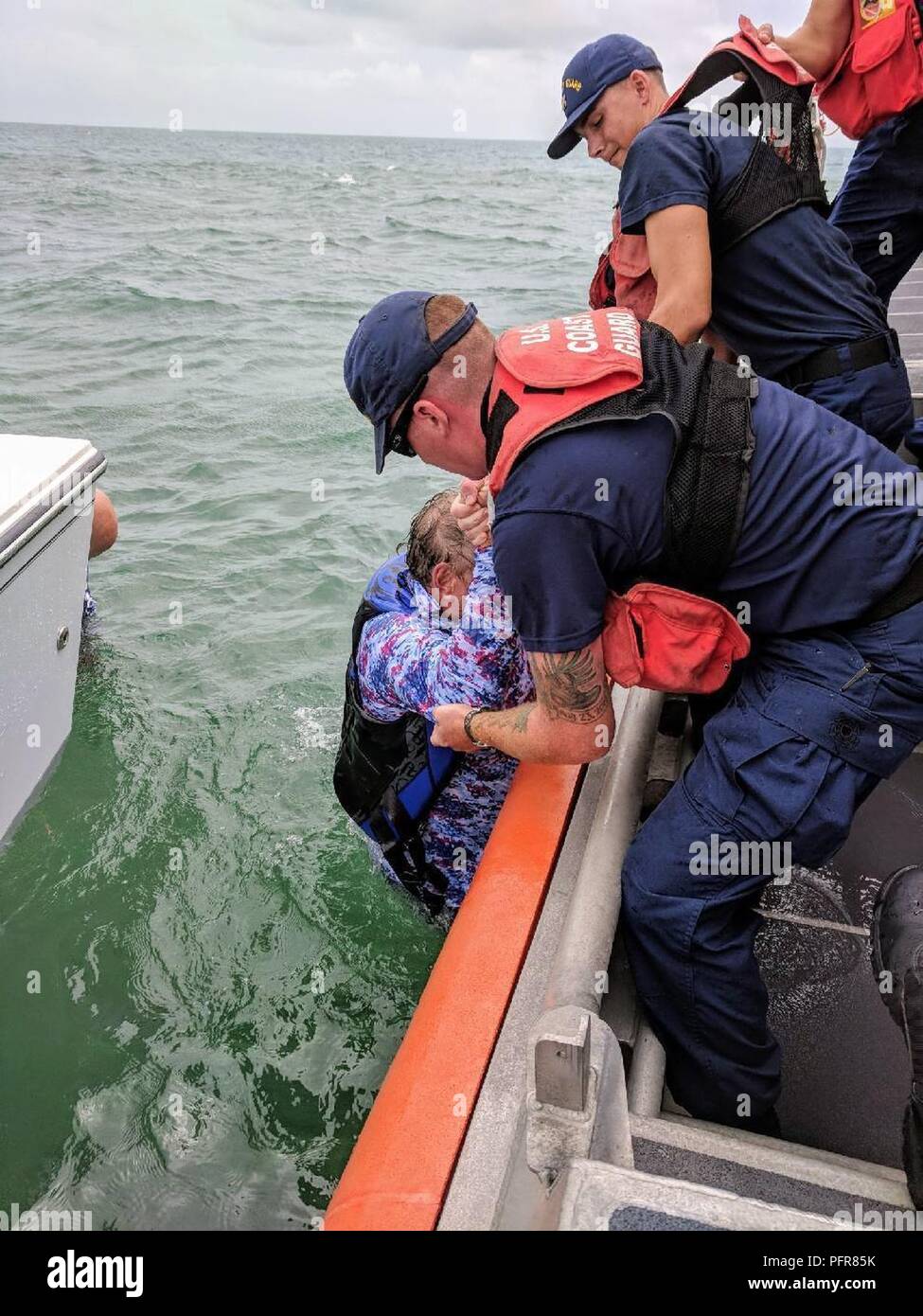 Marathon de la Garde côtière de sauvetage des équipages un plaisancier après leur bateau retourné près de Marathon, en Floride. Un bon Samaritain a aidé à sauver un autre navigateur. Banque D'Images