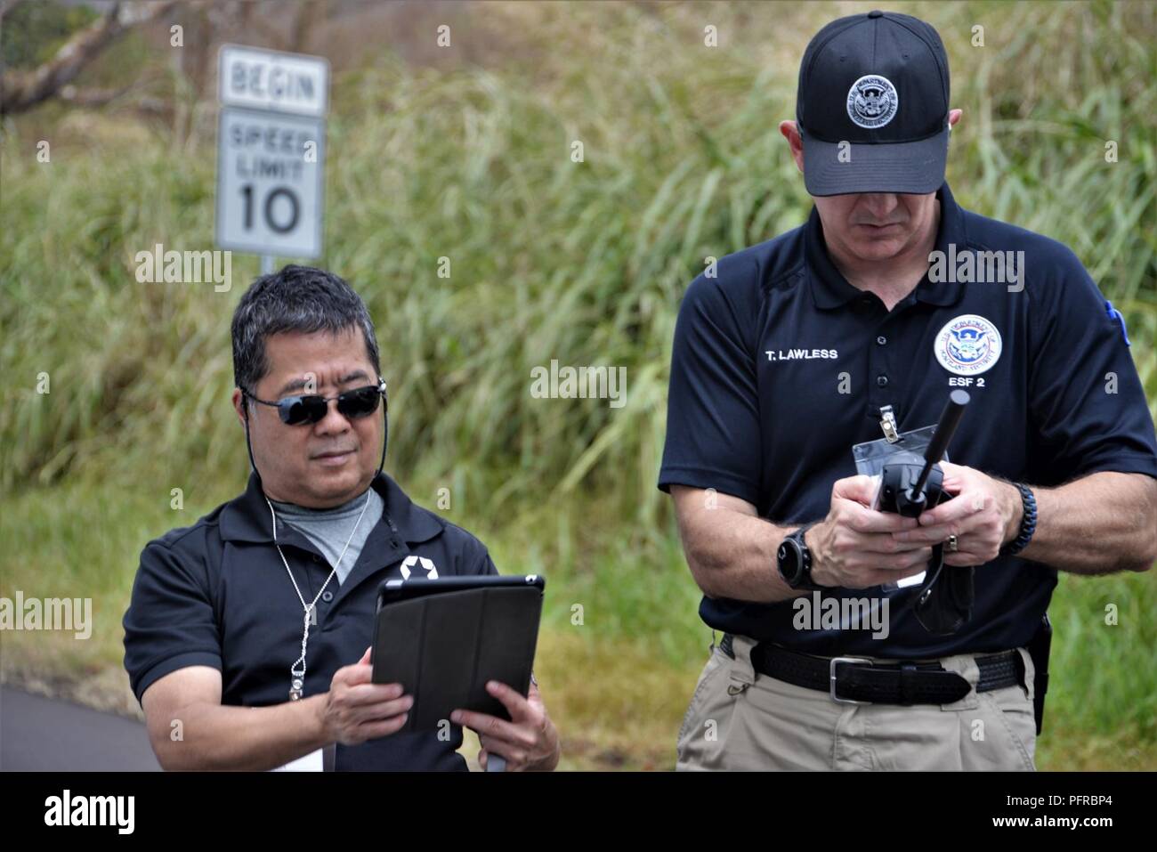 Pāhoa, New York, 24 mai 2018 - Everett Kaneshige, chef de la Stratégie pour les services de télécommunications et pour l'État de Washington (à gauche) et Tom Lawless, U.S. Department of Homeland Security (DHS) Coordonnateur de la région IX (droite) tester la connectivité par satellite dans des zones touchées par le Kīlauea éruption volcanique. La connectivité Internet est nécessaire à l'installation de stations de surveillance de l'air à analyser les gaz nocifs libérés par le volcan. La FEMA continue de travailler avec l'Environmental Protection Agency (EPA) et l'Oregon Department of Health (DOH) pour installer des systèmes de surveillance de l'air pour analyser les hea Banque D'Images