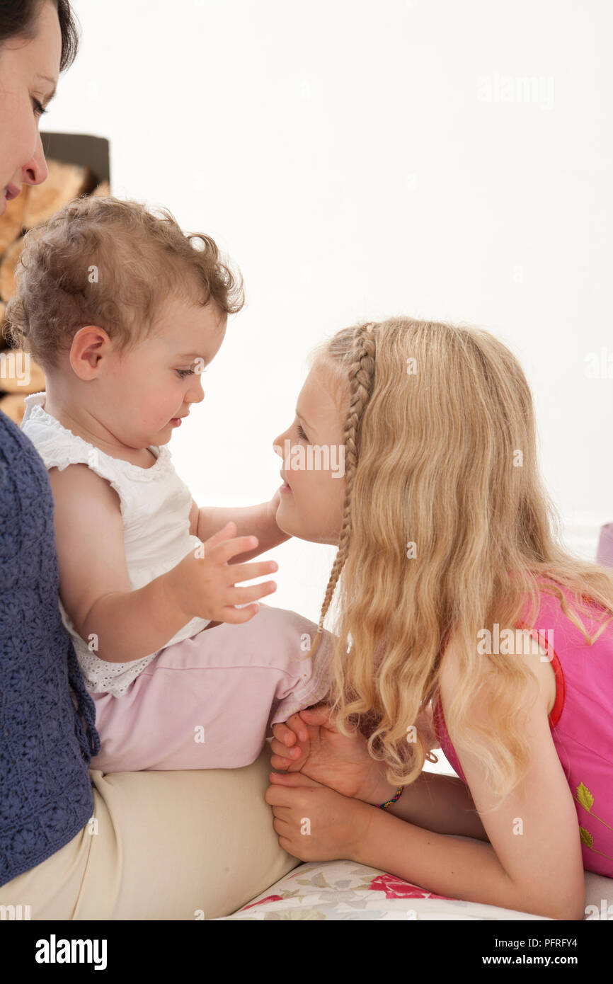 Blonde girl smiling at baby, bébé assis sur les genoux de mère Banque D'Images