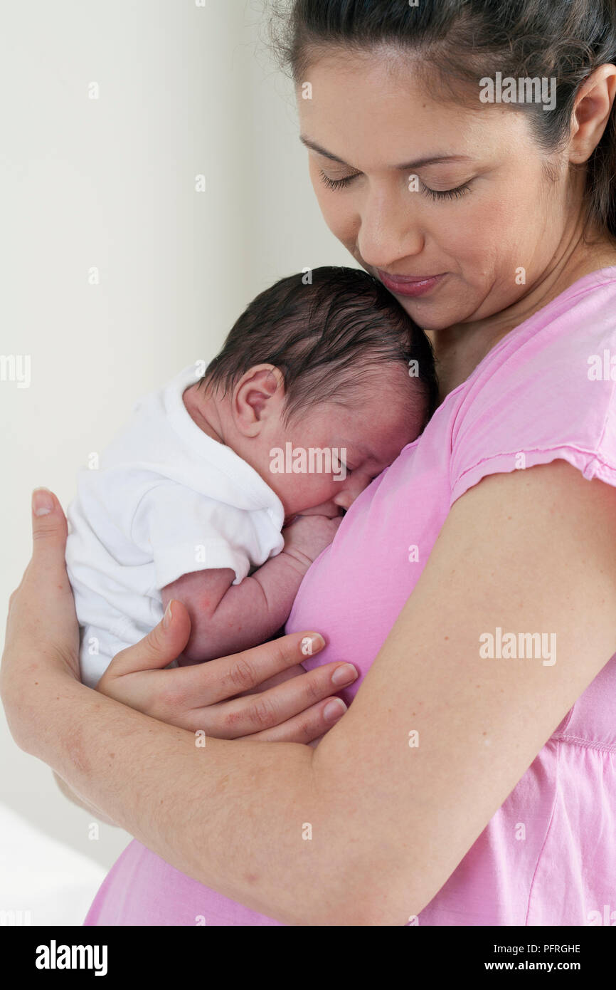 Mère embrassant bébé garçon endormi dans ses bras Banque D'Images