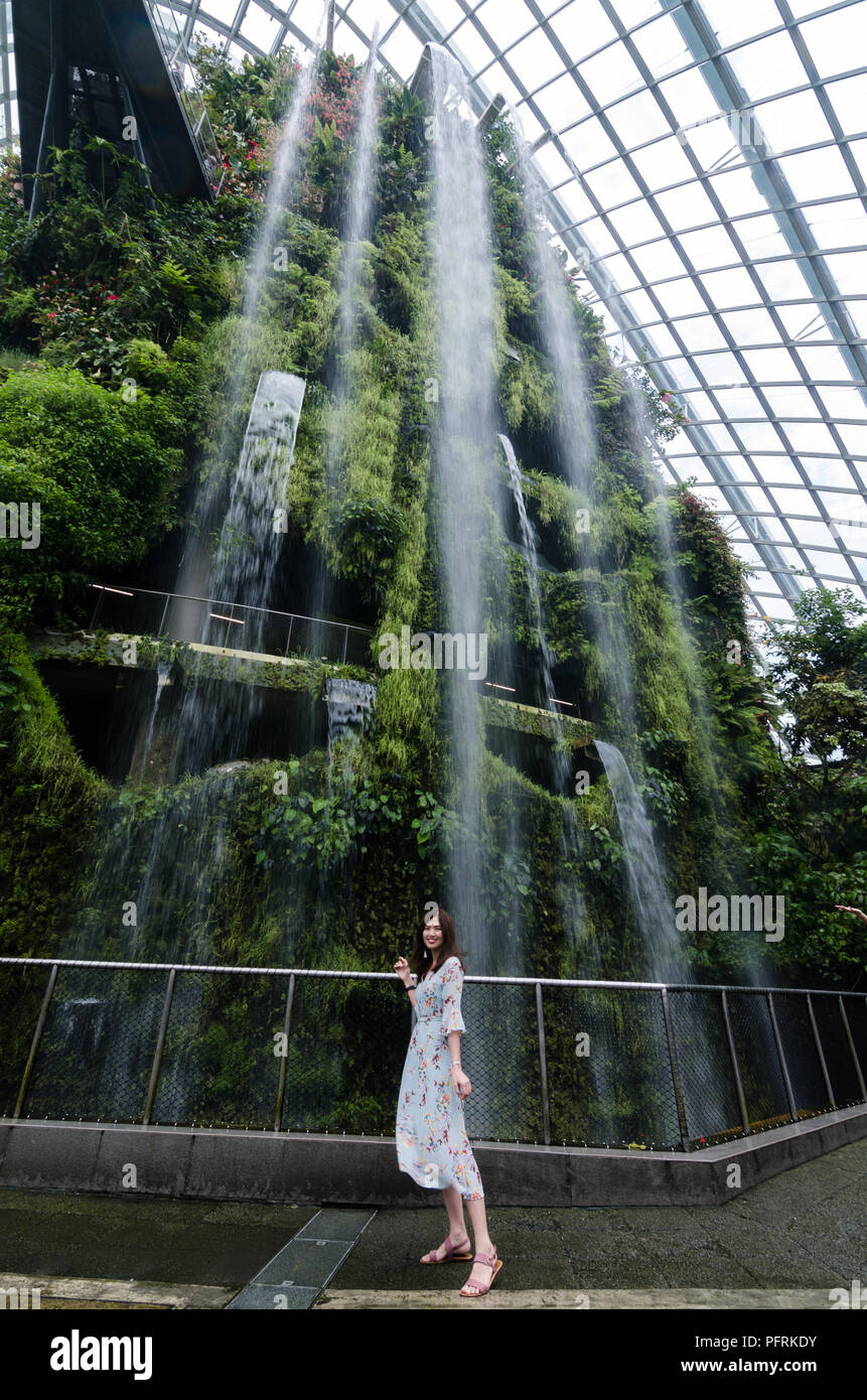 Portrait de belle fille asiatique dans la région de floral dress posing in front of cascade intérieure à Cloud Forrest de jardin par la baie de Singapour. Banque D'Images