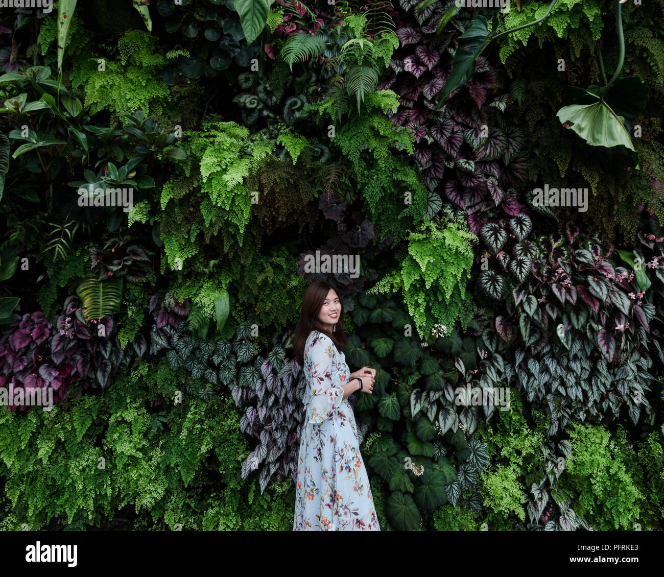 Portrait de belle asiatique fille en robe à fleurs devant un mur végétal de la vie de Forrest Cloud au jardin par la baie de Singapour. Banque D'Images