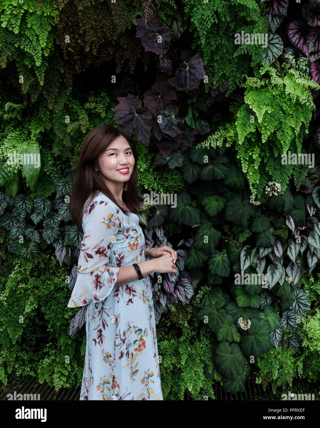 Portrait de belle asiatique fille en robe à fleurs devant un mur végétal de la vie de Forrest Cloud au jardin par la baie de Singapour. Banque D'Images