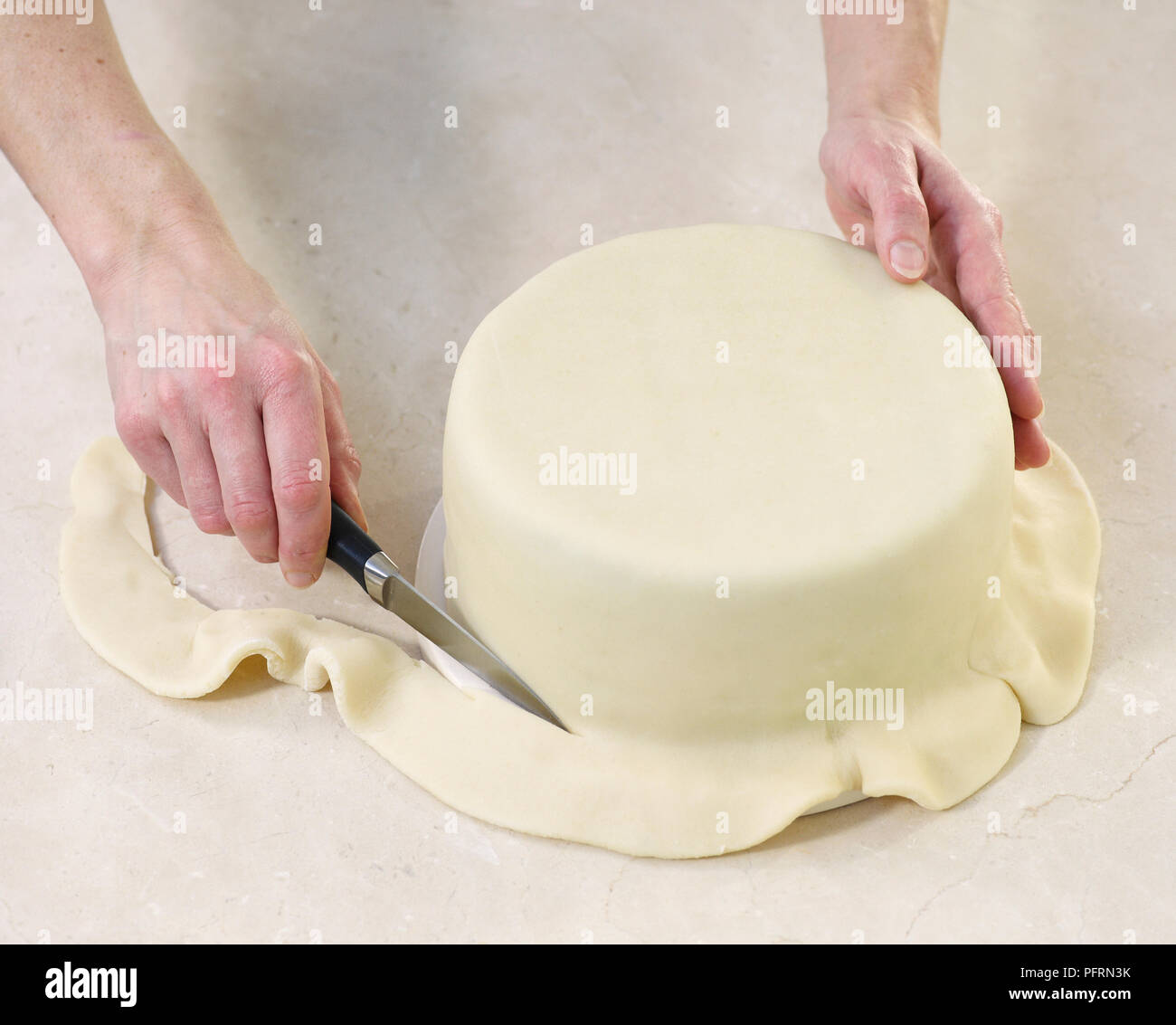 Gâteau de fruit recouvert de massepain, coupe manuelle l'excédent de pâte au fond du moule à gâteau, close-up Banque D'Images