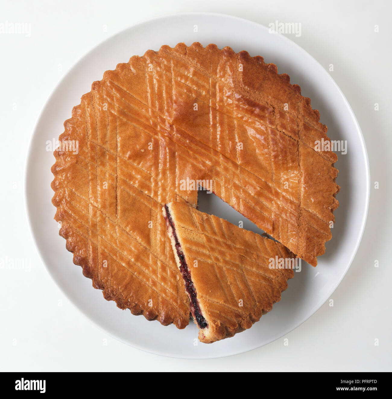 Gâteau Basque gâteau rempli de confiture de cerises noires sur plaque blanche avec slice Banque D'Images