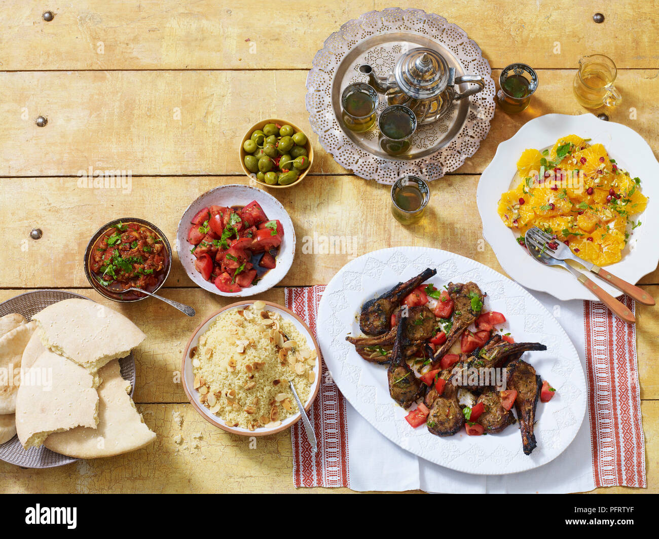 Dîner marocain, y compris l'zahlouk (aubergine dip), kesra (pain), kesksou (couscous), lahma meshwi (agneau), les olives, le thé à la menthe, salade d'oranges a la marocaine Banque D'Images