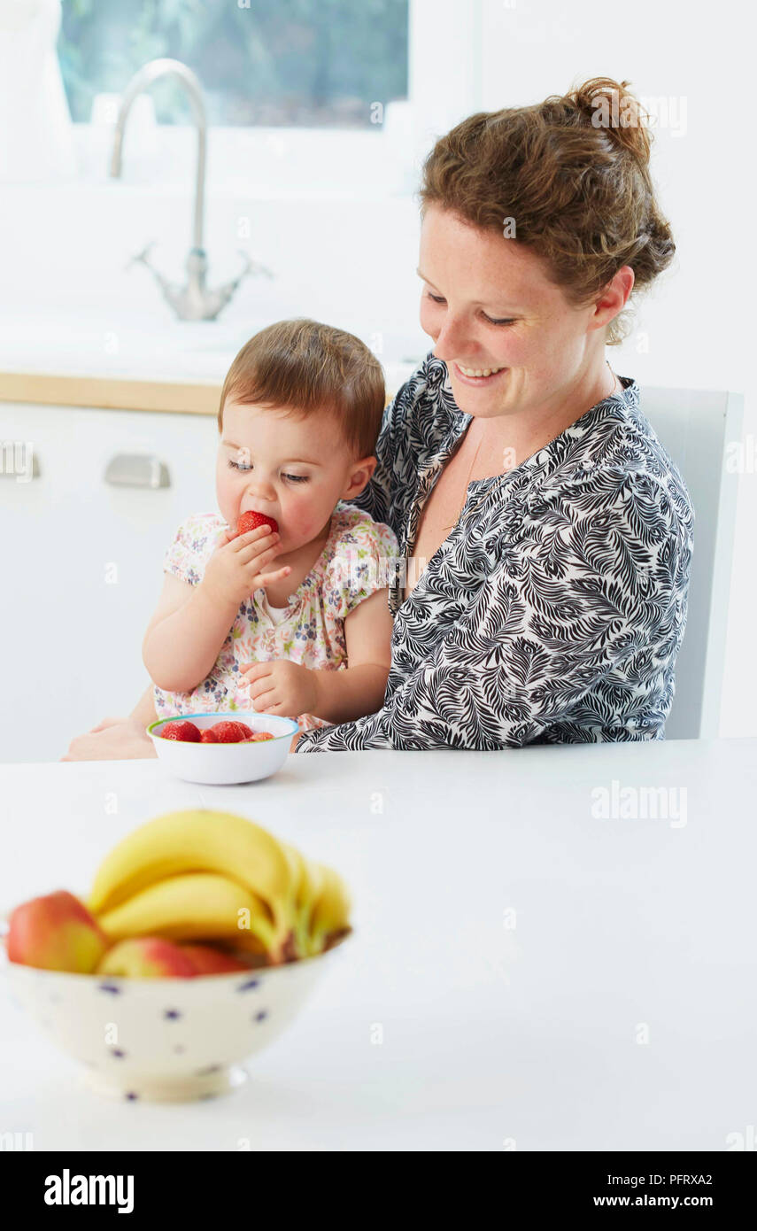 Mère avec bébé manger des fruits (modèle de 18 mois) Banque D'Images