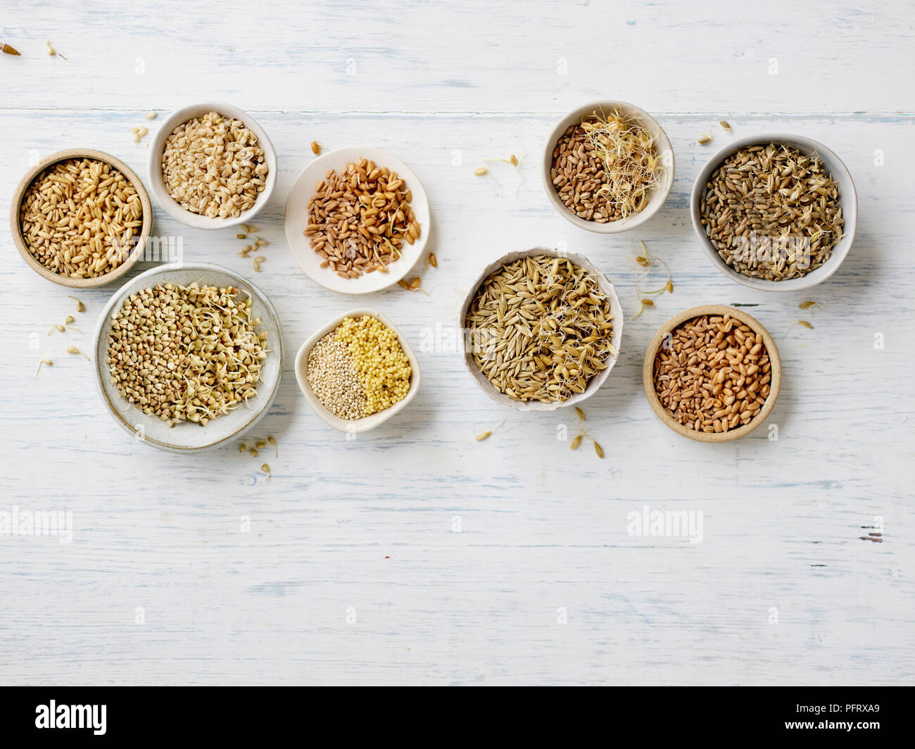 Les grains germés et unsprouted dans des bols sur fond en bois blanc Banque D'Images