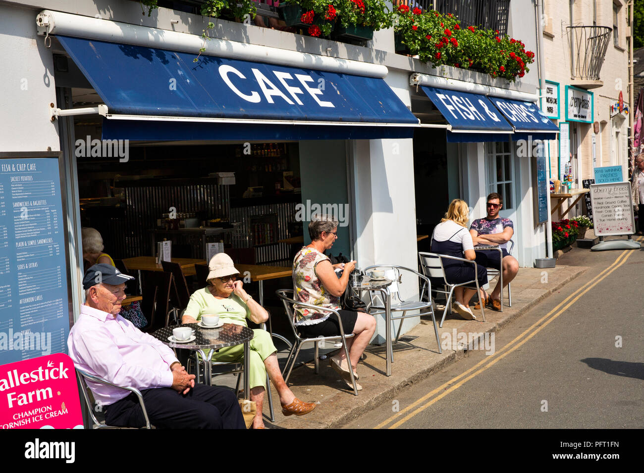 UK, Cornwall, Padstow, le Strand, les visiteurs assis au soleil à l'extérieur du poisson au bord de l'eau et Chip shop Banque D'Images