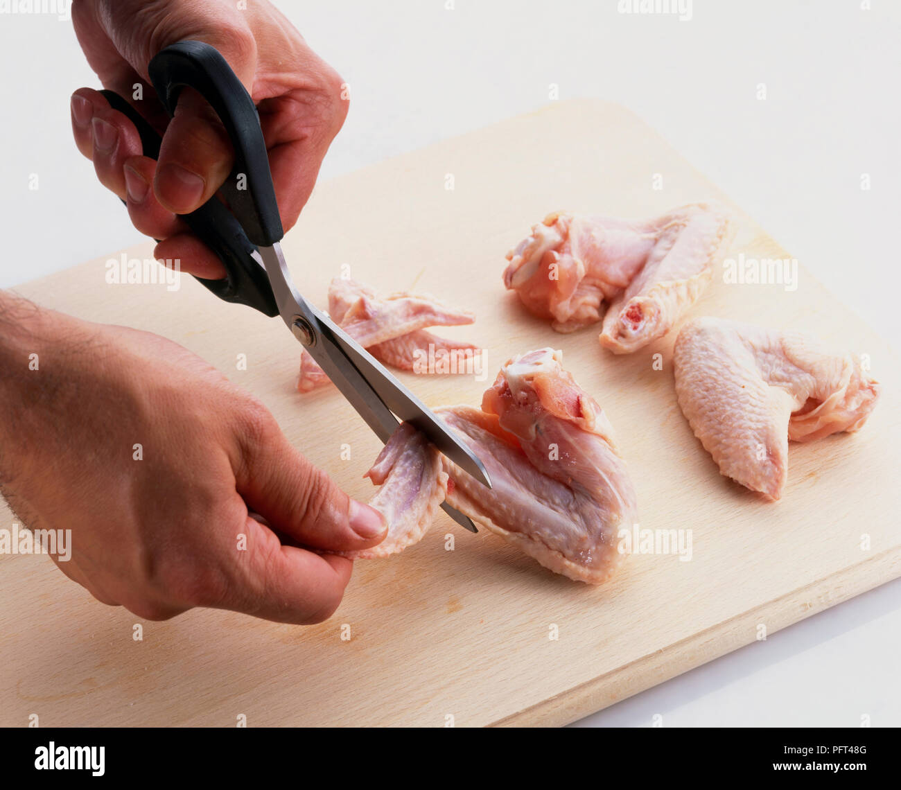 A l'aide de ciseaux pour enlever les ailes de poulet sur les conseils de planche à découper en bois, close-up Banque D'Images