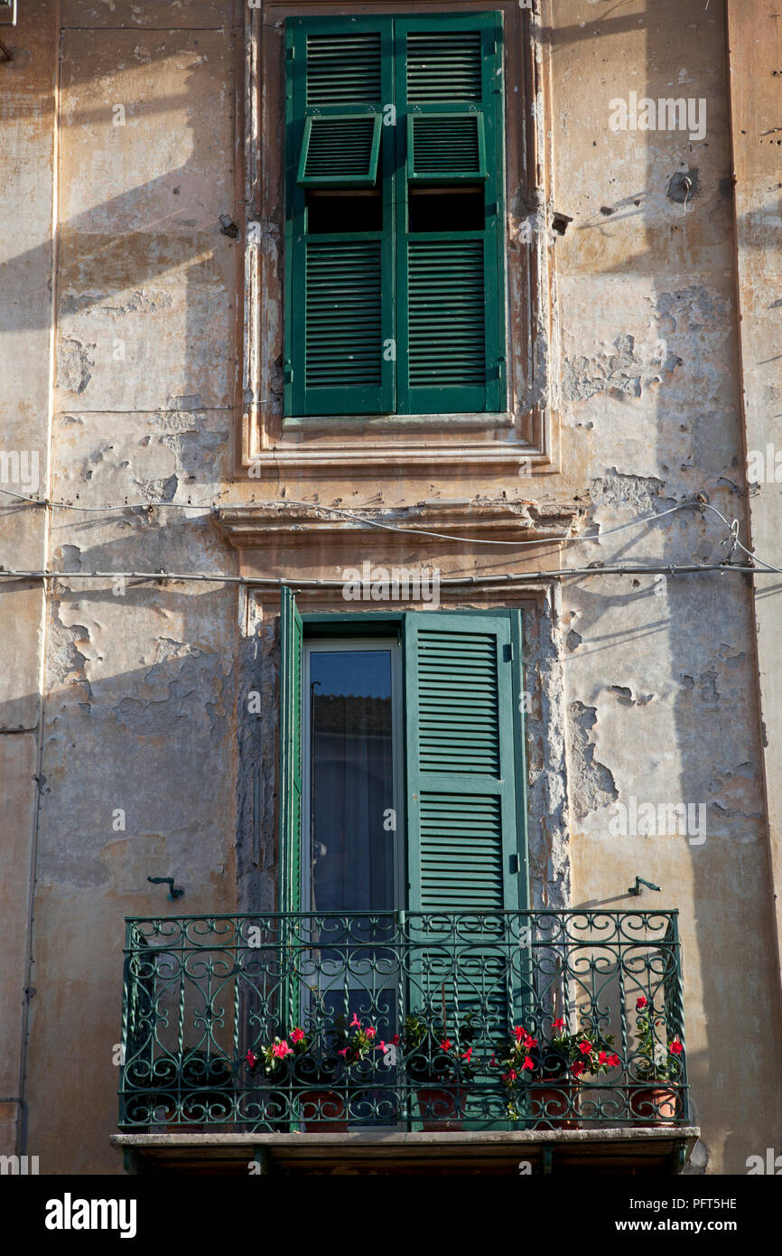 L'Italie, Viterbe, Latium, vert balcon avec des plantes en pot et des volets verts sur la fenêtre ci-dessus sur l'ancien bâtiment en partie historique de la ville de Tarquinia Banque D'Images