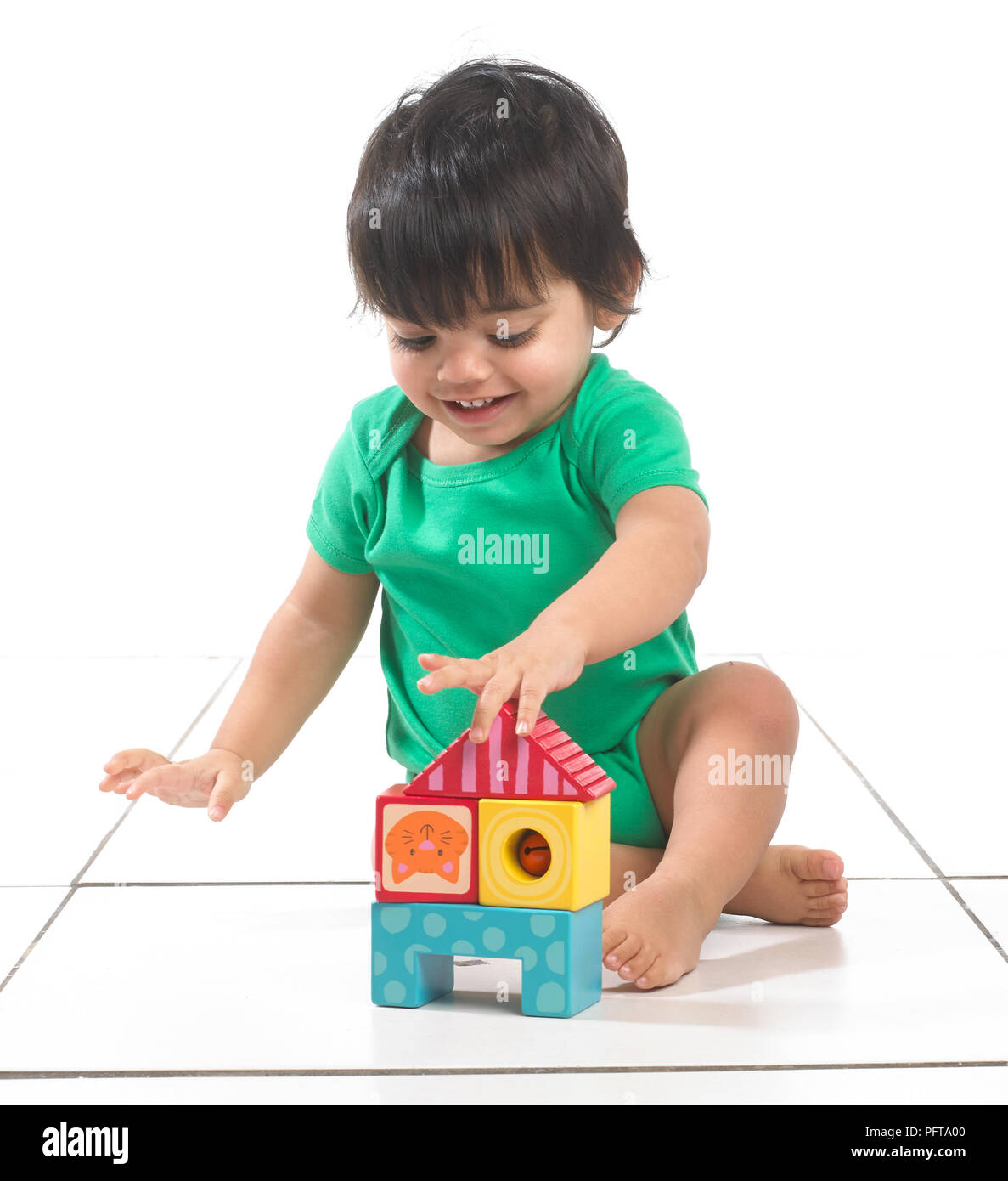 Bébé garçon (16 mois) assis à jouer avec des blocs de construction Banque D'Images