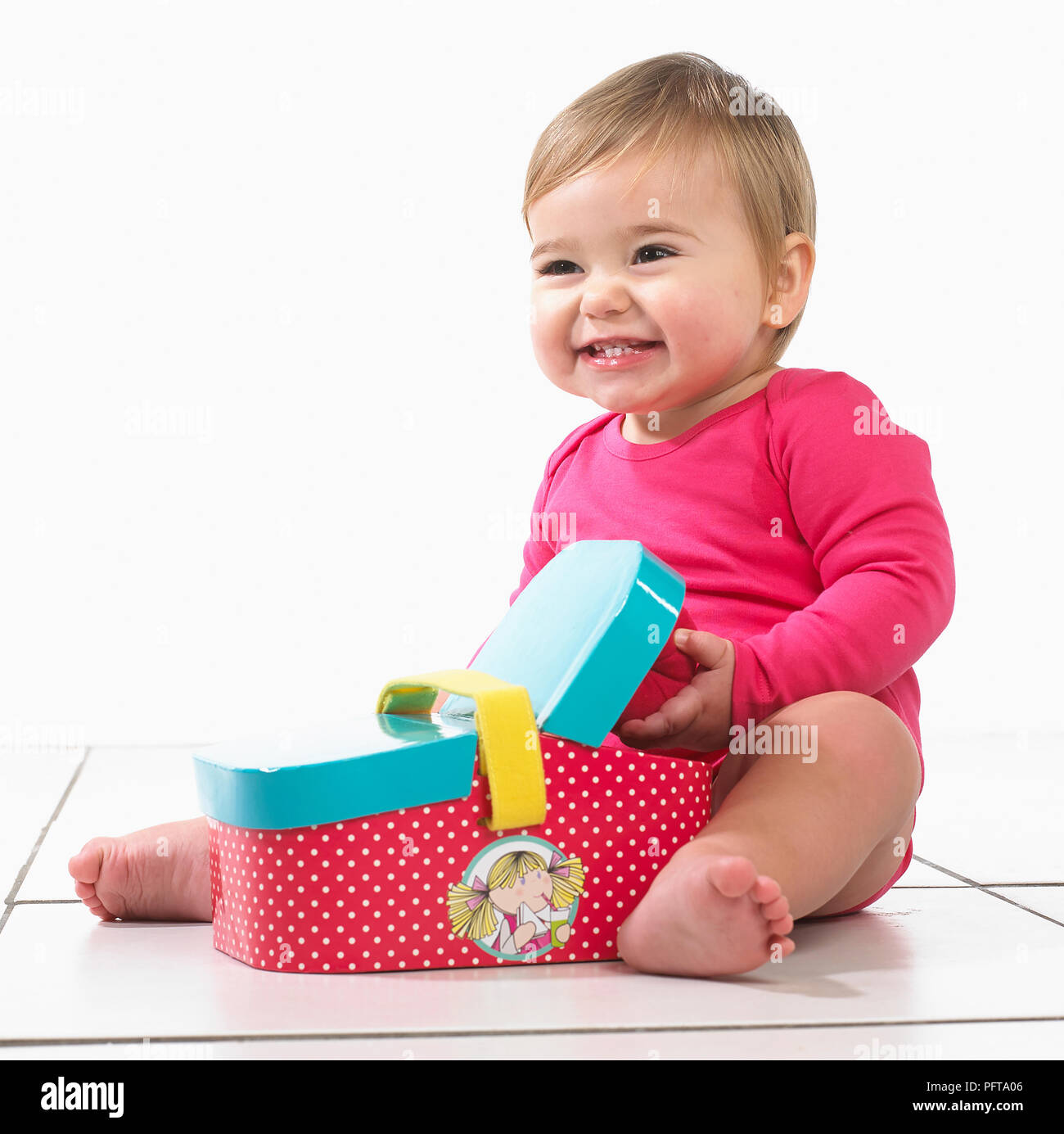 Bébé fille (12 mois) sitting Playing with toy panier pique-nique Banque D'Images