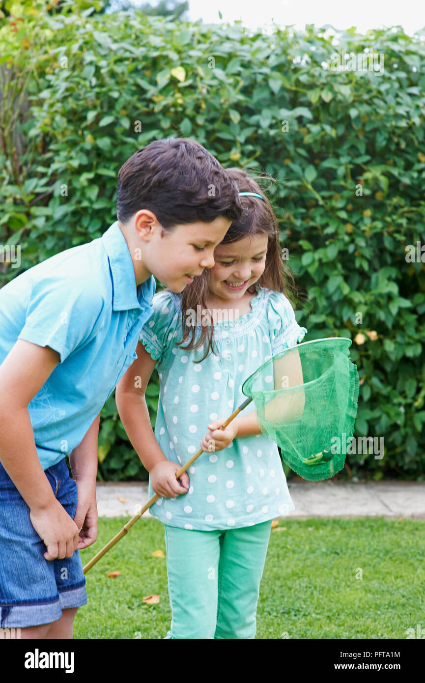 Boy and girl looking at grenouille en filet de pêche Banque D'Images