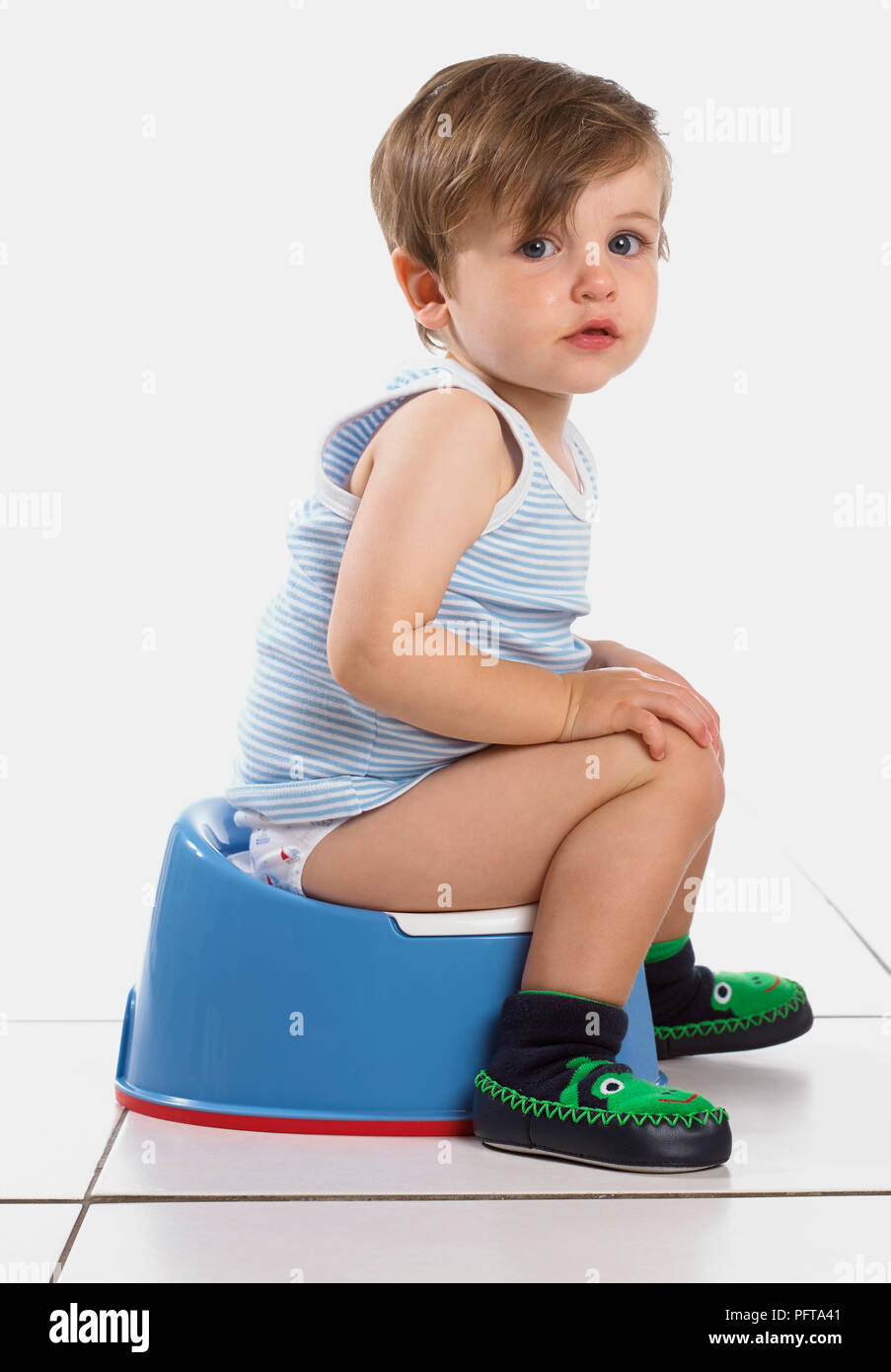 Garçon assis sur un pot bleu, 20 mois Banque D'Images