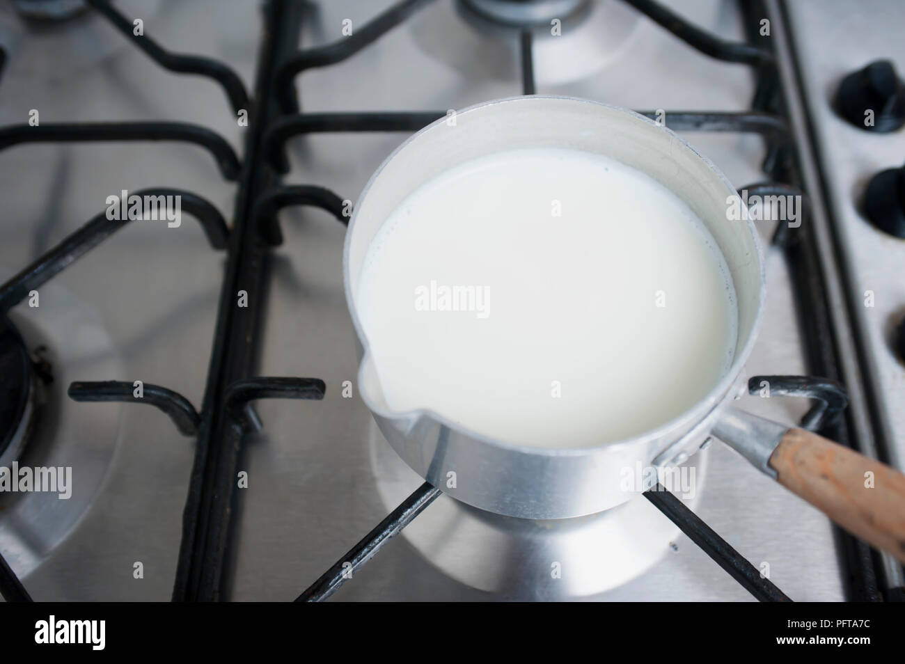 Réchauffement de la lait dans une casserole sur une cuisinière. Banque D'Images