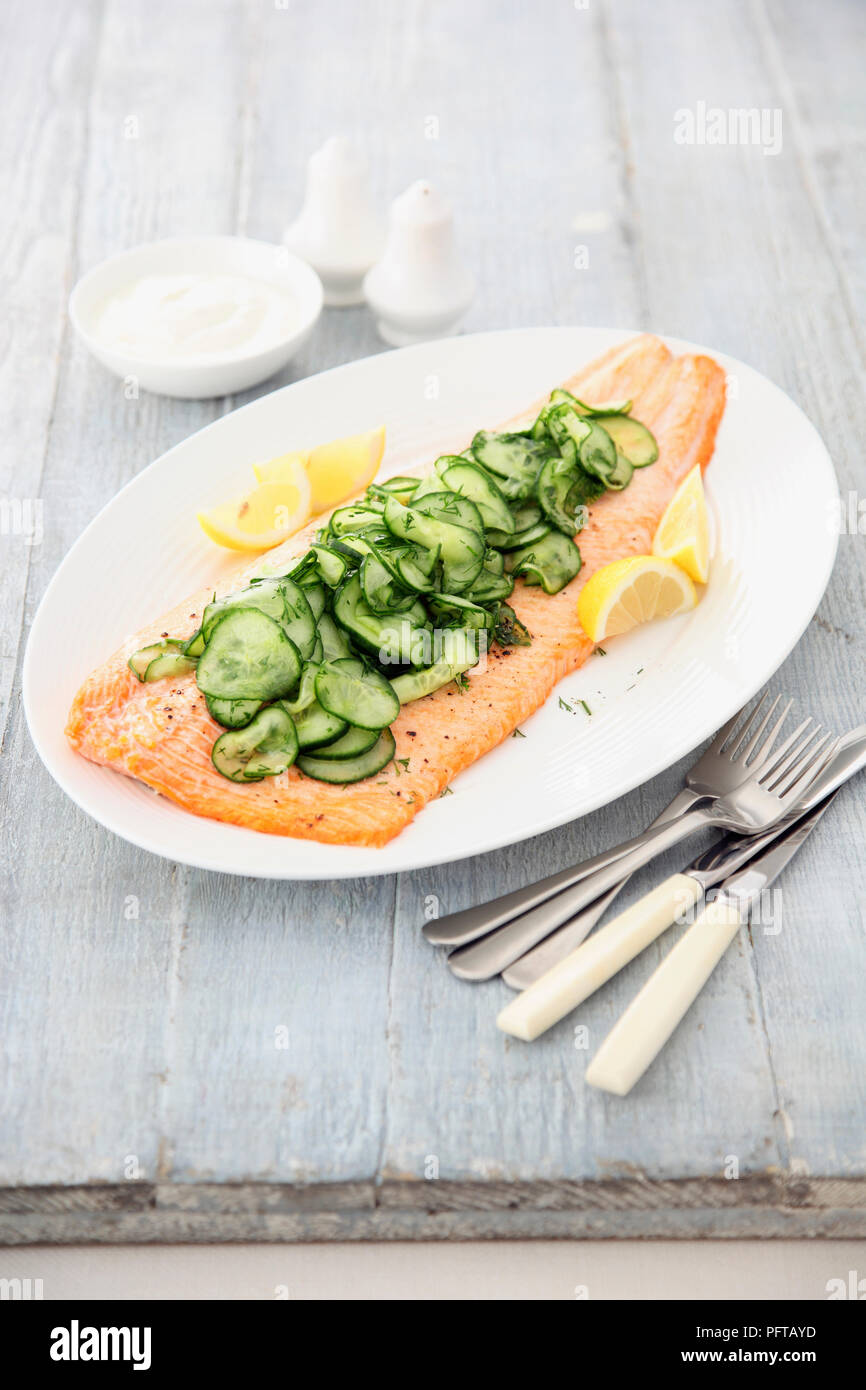 Saumon rôti au four garnie de concombres Banque D'Images