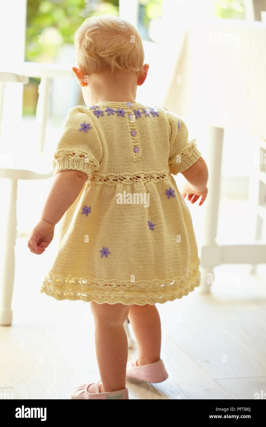Faire le pas de bébé fille robe en maille jaune 17 mois Banque D'Images
