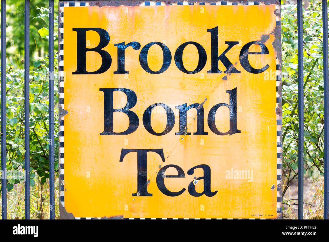 Gros plan de l'affiche publicitaire en émail d'époque, signalisation fixée aux rampes à l'extérieur de la gare ferroviaire « Brooke Bond Tea » - antiquités britanniques. Banque D'Images