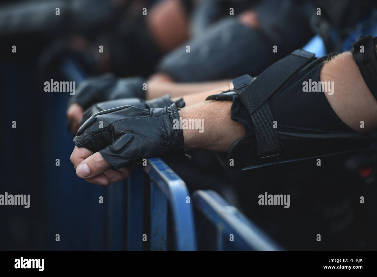 Agent de police les mains sur une clôture de sécurité au cours d'une émeute Banque D'Images