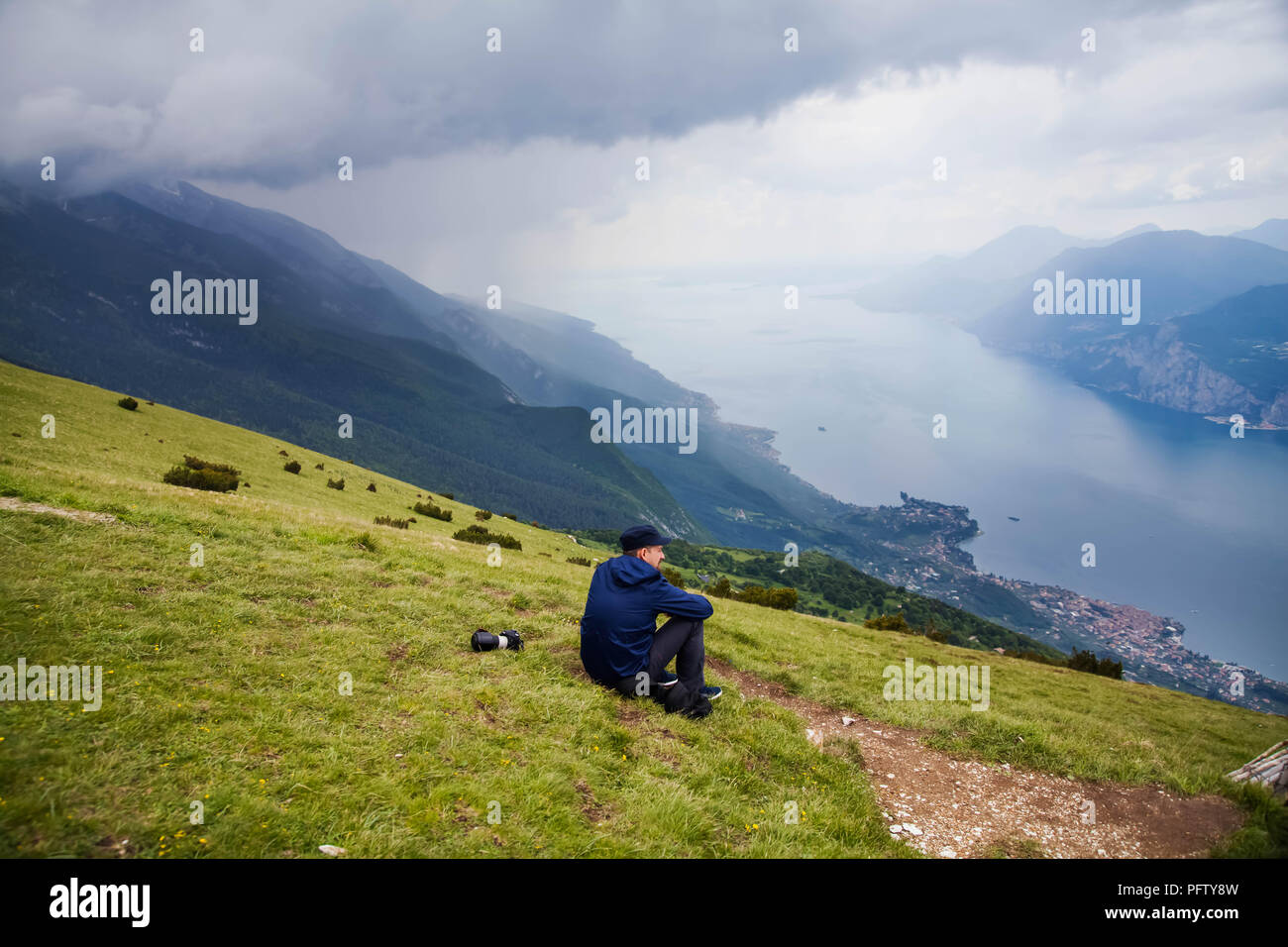 Traveler détente sur le haut d'une colline,regarder un paysage magnifique de montagnes et le lac paysage. Des vacances d'été, voyager concept Banque D'Images