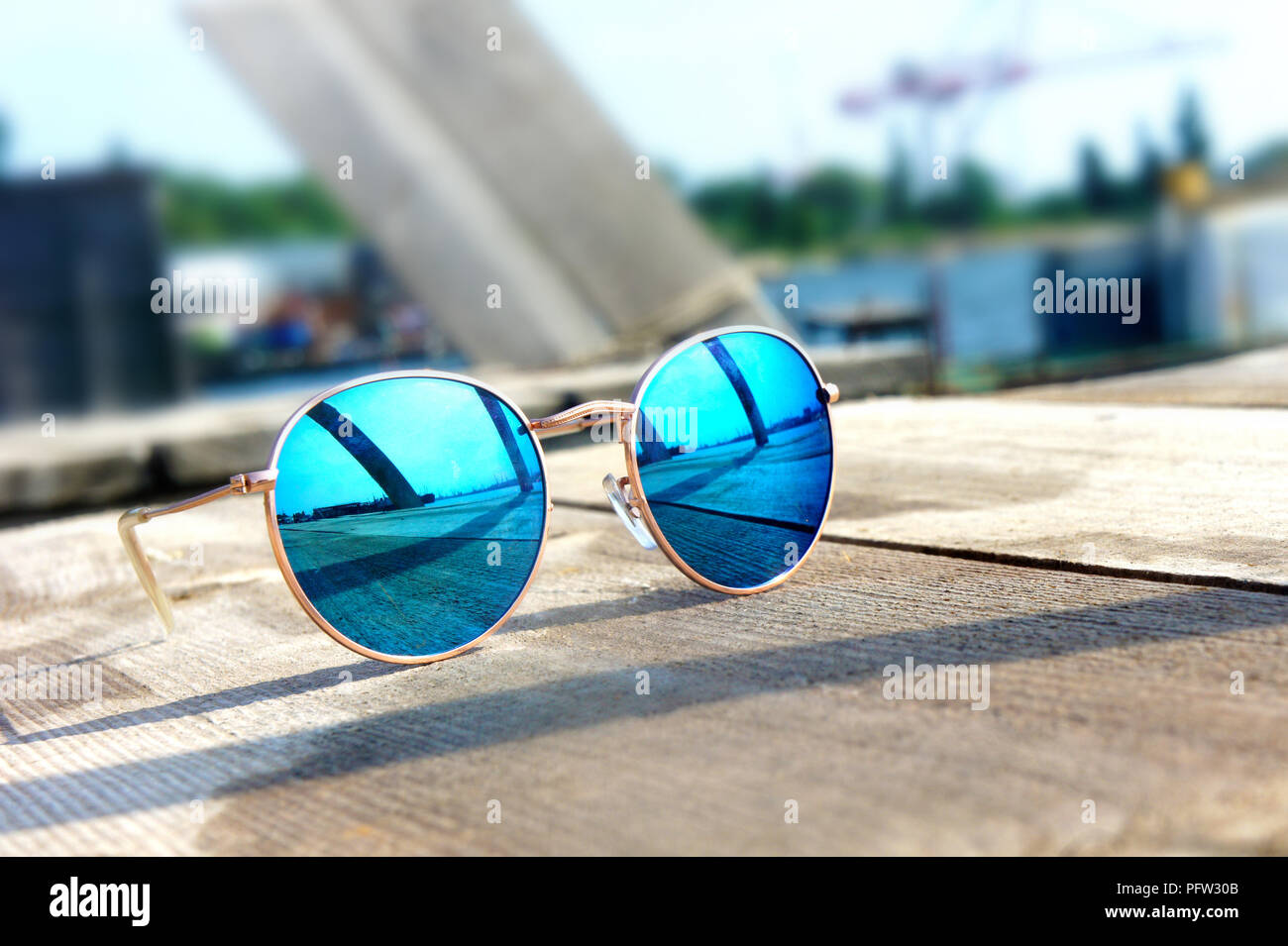 Miroir à la mode lunettes avec verres bleus sur le soleil se coucher sur un  sol en bois reste voyage reflète dans verres Photo Stock - Alamy
