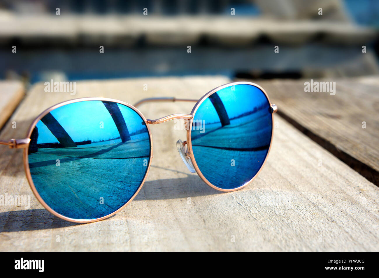 Miroir à la mode lunettes avec verres bleus sur le soleil se coucher sur un  sol en bois reste voyage reflète dans verres Photo Stock - Alamy