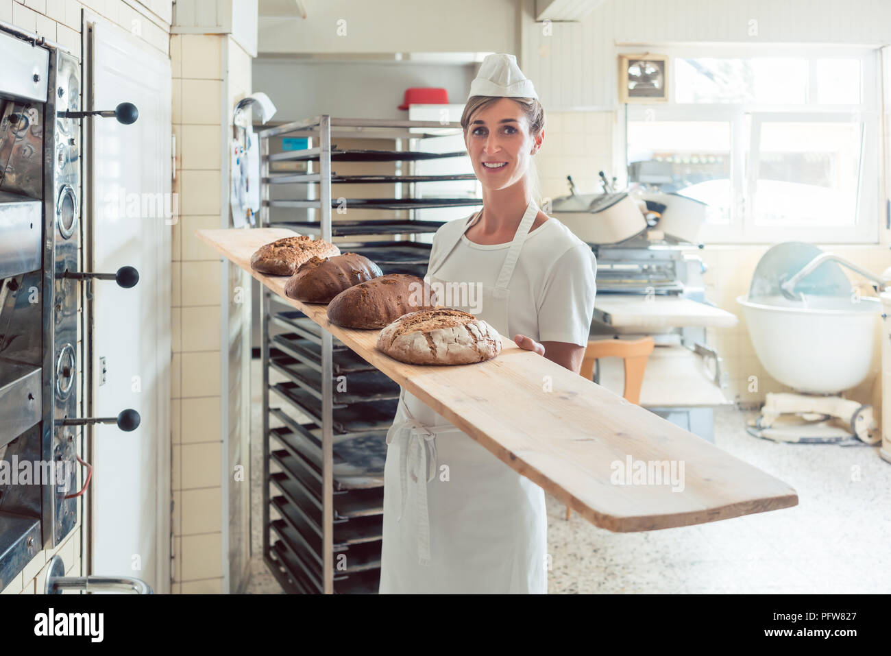 Baker femme présentant à bord du pain dans une boulangerie Banque D'Images