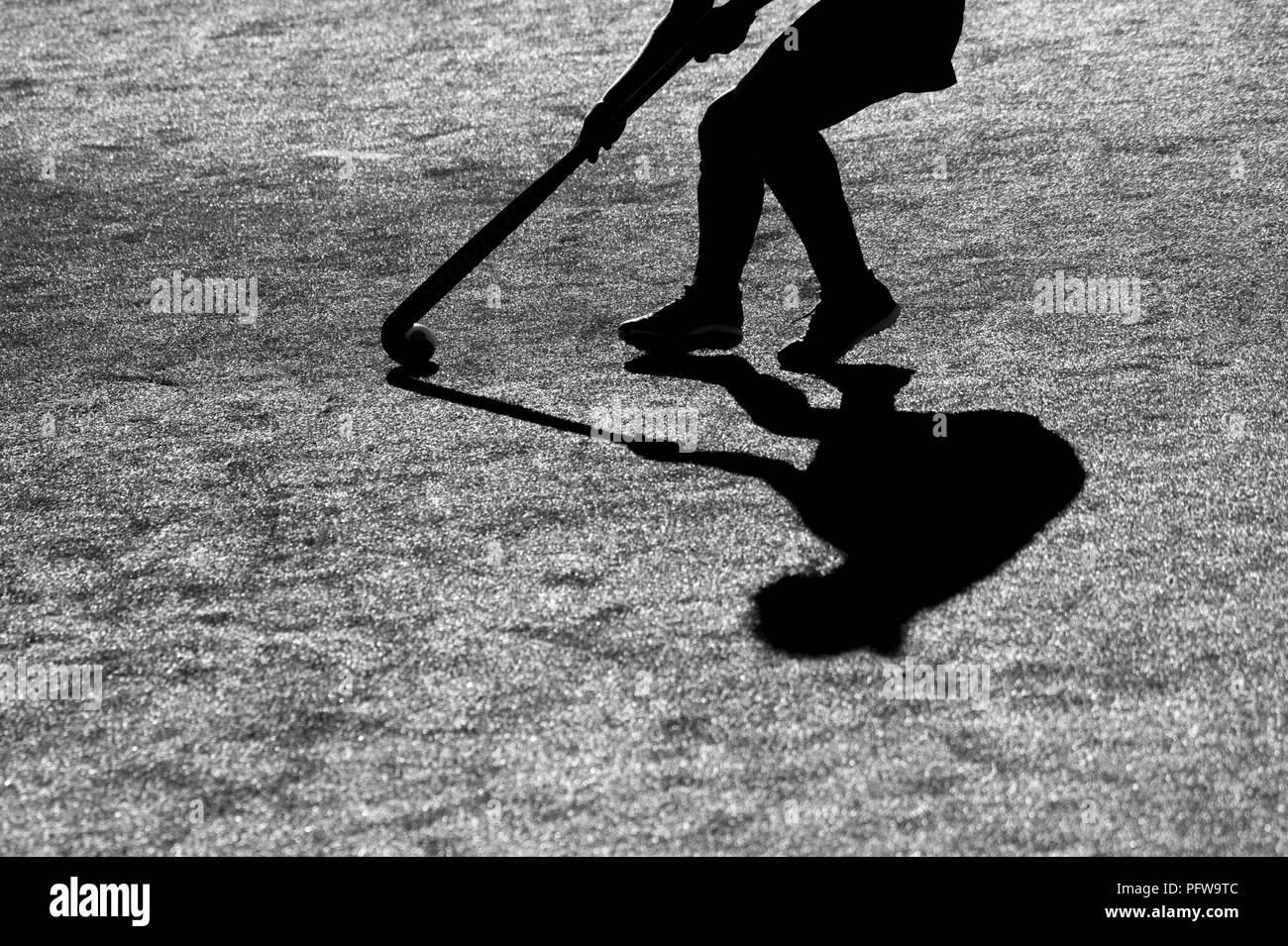 Silhouette. L'ombre d'un joueurs de hockey est en cours d'exécution avec un bâton de hockey sur un terrain de hockey. Banque D'Images