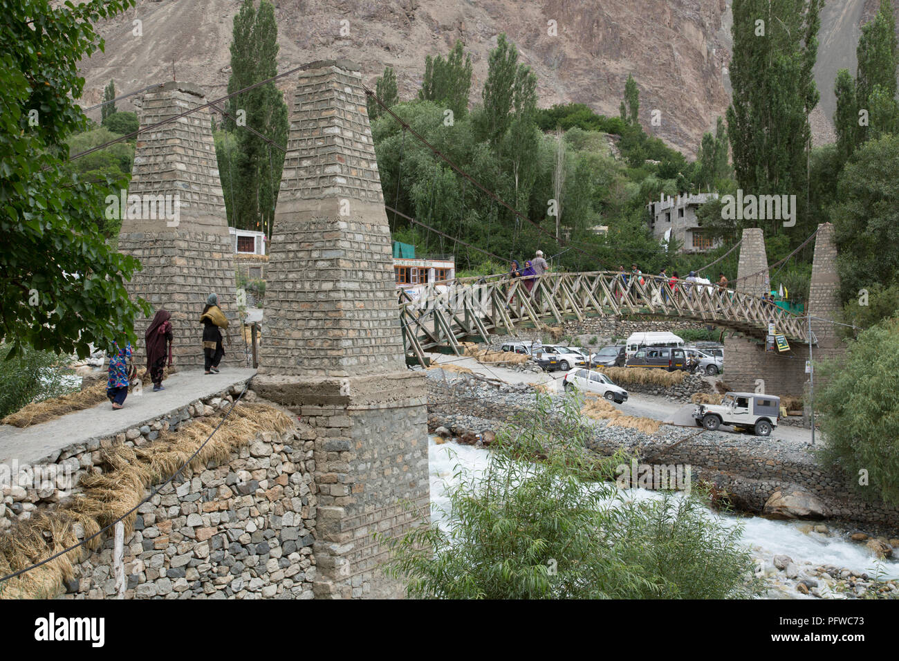 Un pont suspendu en bois avec des piles en pierres de passage à niveau d'un affluent de la rivière à Turtuk fleuves Shyok, village de la vallée de fleuves Shyok, Ladakh, le Jammu-et-Cachemire, l'Inde Banque D'Images