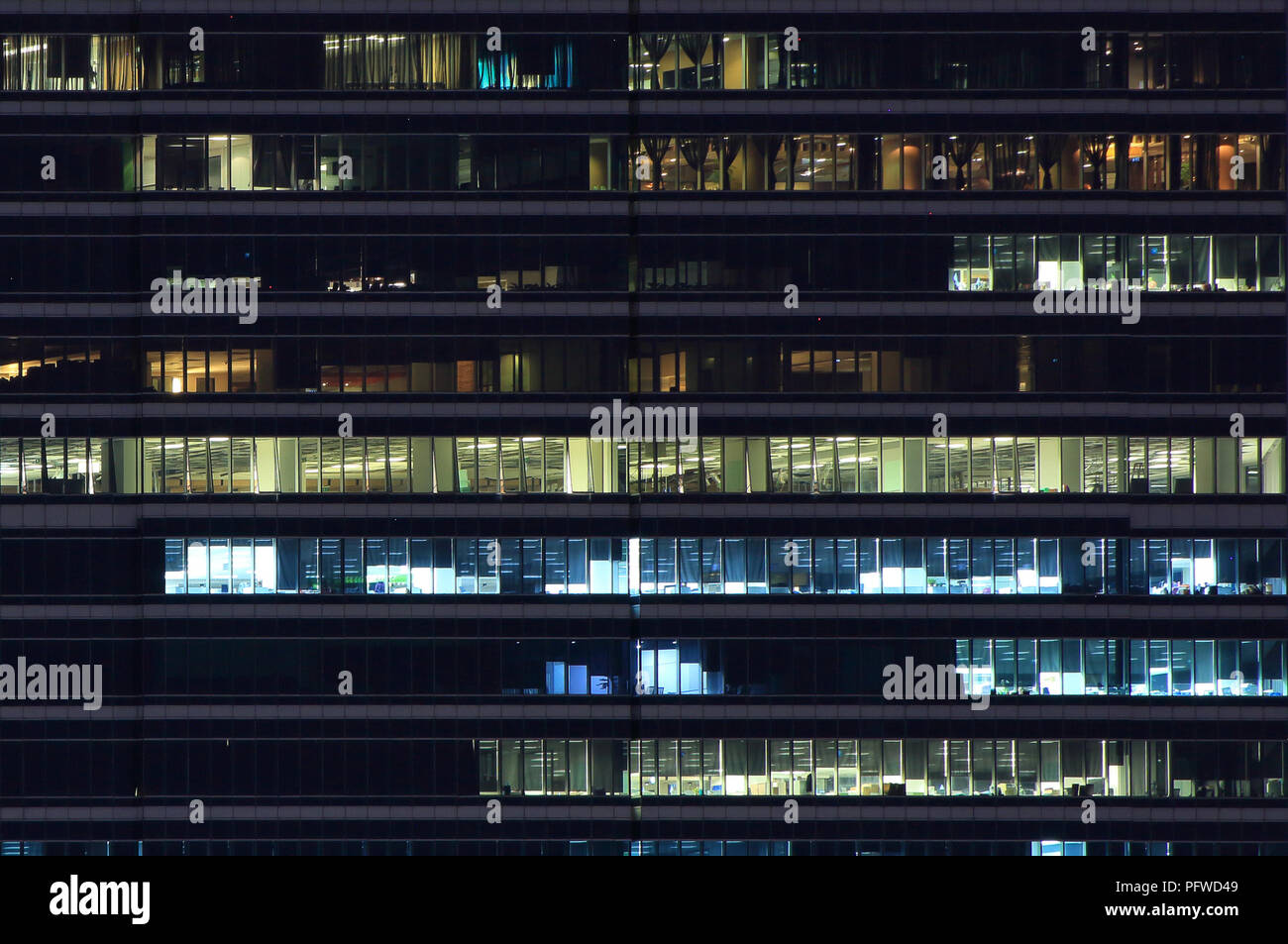 Les travailleurs d'un immeuble de bureaux. boîte de lumière la nuit. logement bâtiment moderne en verre et metal clad office building s'allumer le soir. Banque D'Images
