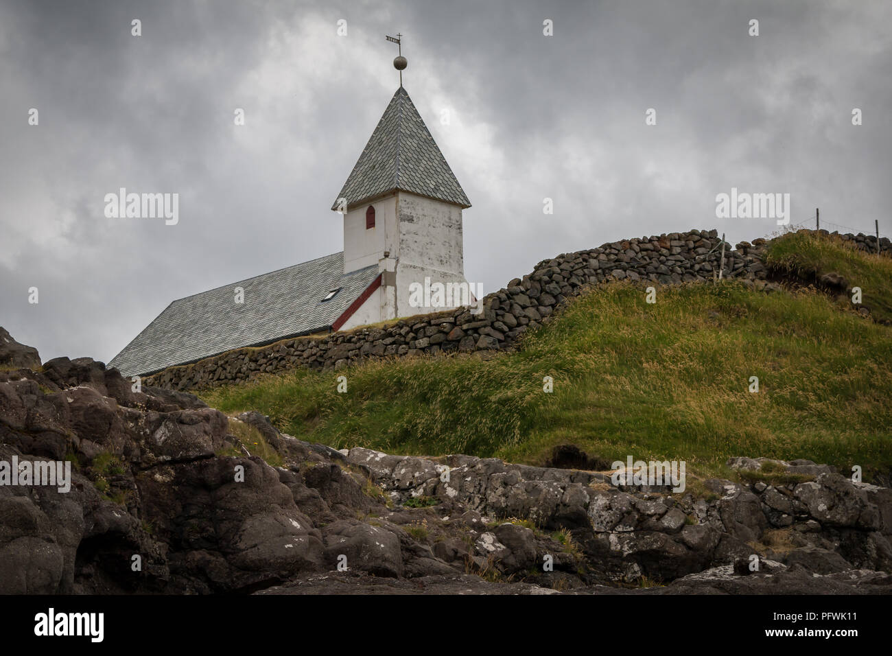 Et c'est l'Église Viðareiði mur de pierre au-dessus d'une falaise sur le bord de l'Atlantique Nord, Viðareiði, île de Viðoy, Îles Féroé Banque D'Images