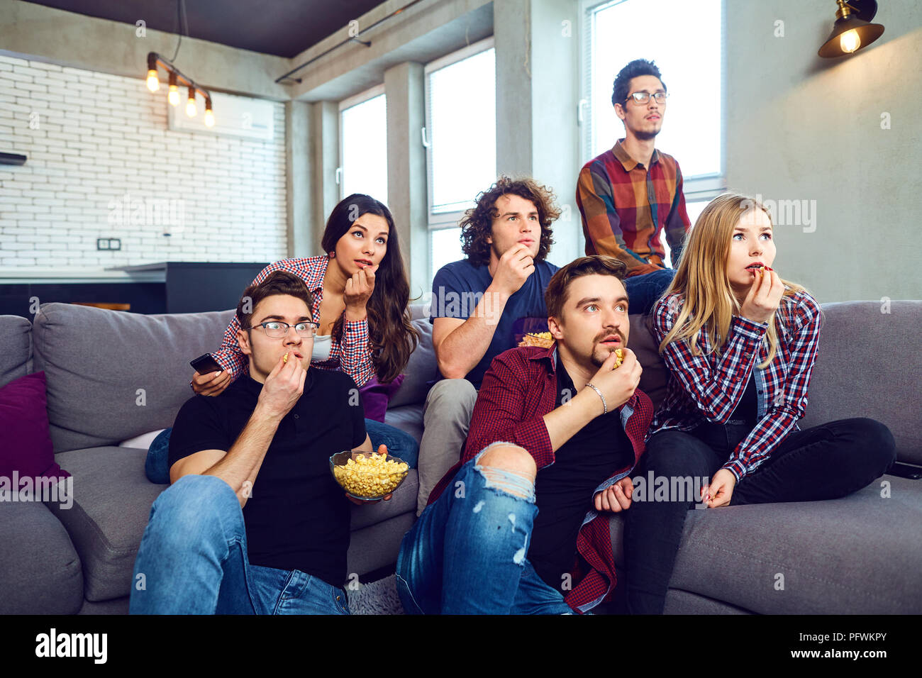 Un groupe d'amis eating pizza wathing tv dans la chambre. Banque D'Images