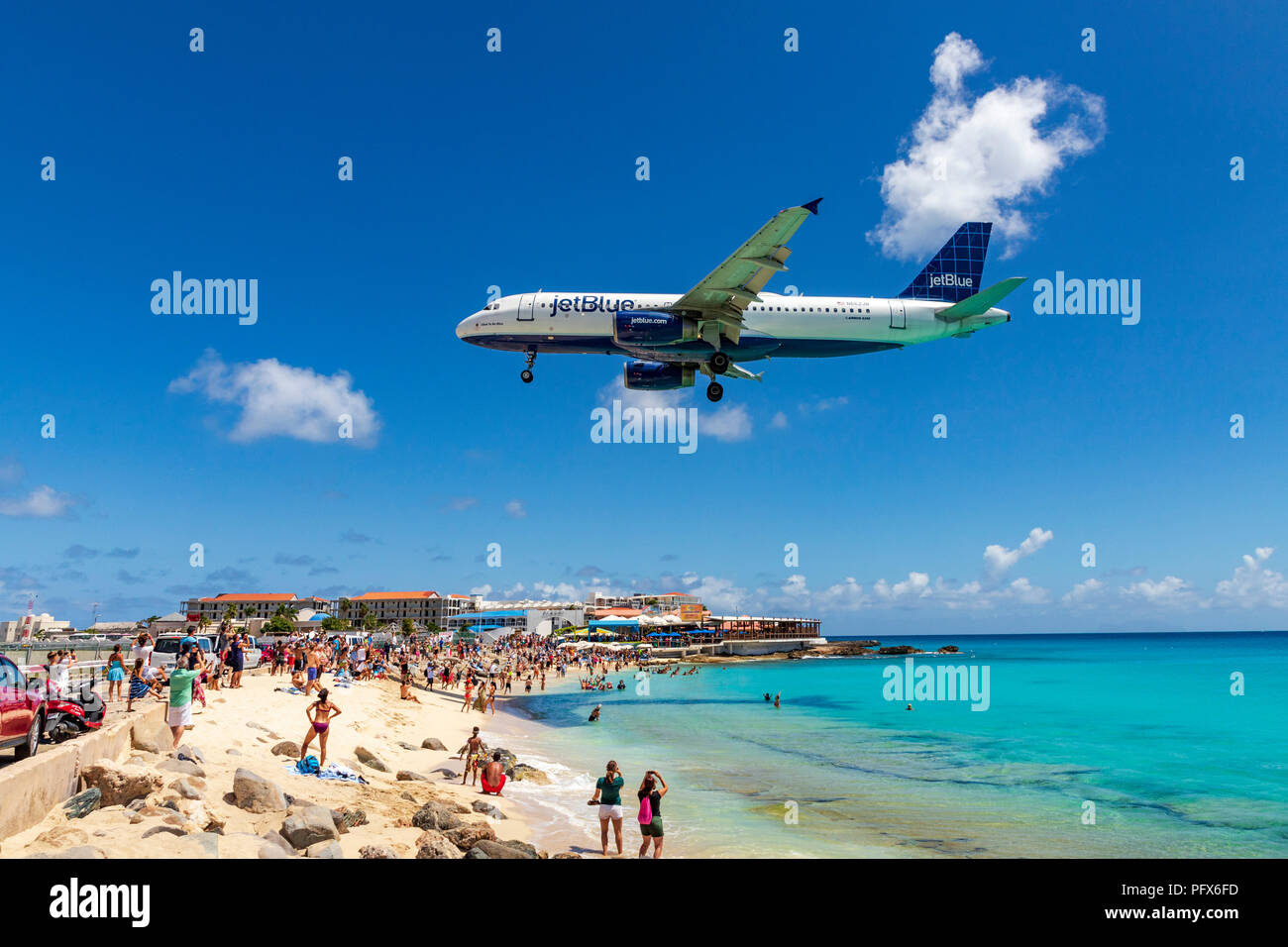 Un vol Jetblue passe au-dessus de la plage Maho et des dizaines de touristes juste avant l'atterrissage à l'Aéroport International Princess Juliana à Saint Martin. Banque D'Images