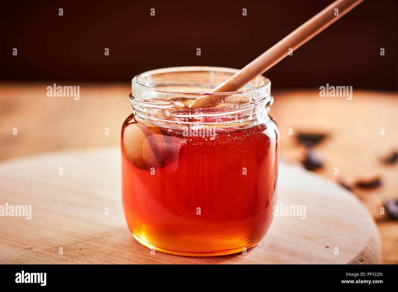 Pot en verre avec plein de miel. Prendre le miel avec une cuillère de bois Banque D'Images