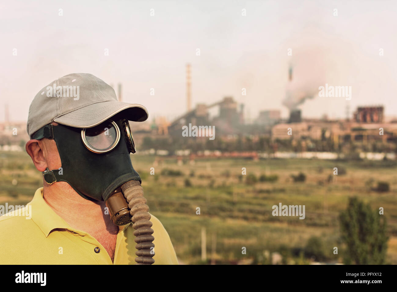 L'homme en masque à gaz et cap sur l'usine industrielle et l'arrière-plan pipe. Retro style tonique de l'image. Banque D'Images