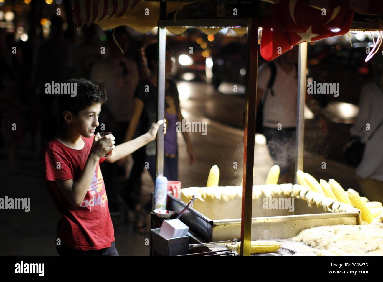 Istanbul, Turquie 21 juillet 2018. Un garçon la vente de maïs chaud à Istanbul la nuit, de boire du thé turc Banque D'Images