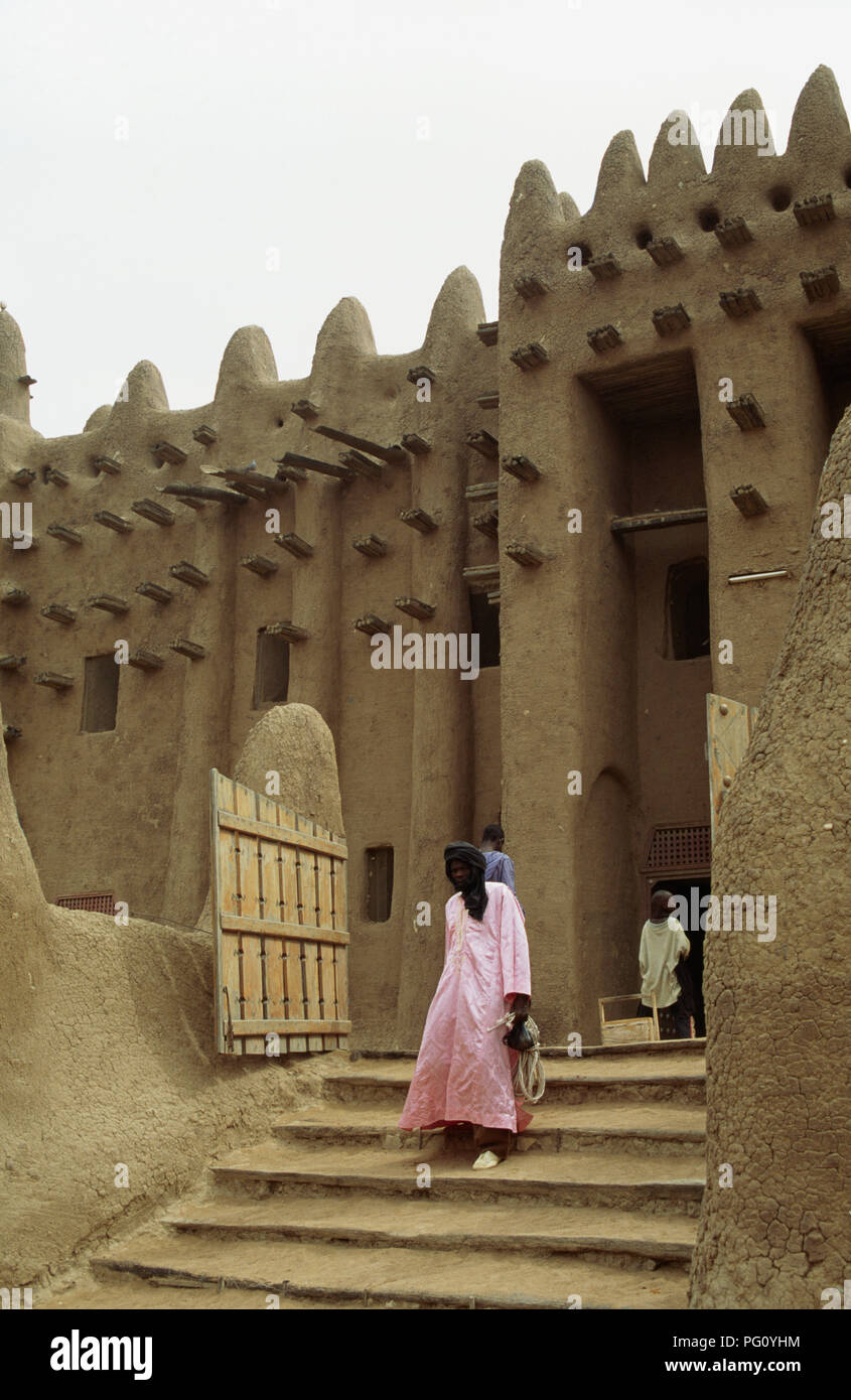 Homme portant la robe rose en descendant les marches de la Grande Mosquée de Djenné, au Mali pour un usage éditorial uniquement Banque D'Images