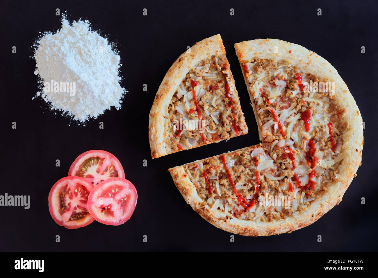 Thon au four pizza, tas de farine et de tranches de tomate sur fond noir Banque D'Images