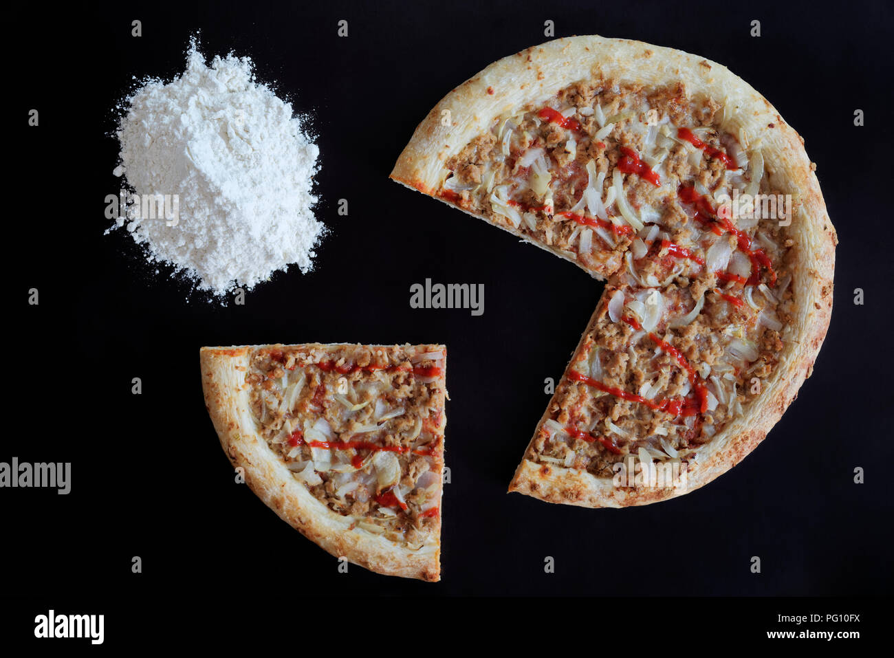 Pizza au thon cuit et tas de farine sur fond noir Banque D'Images