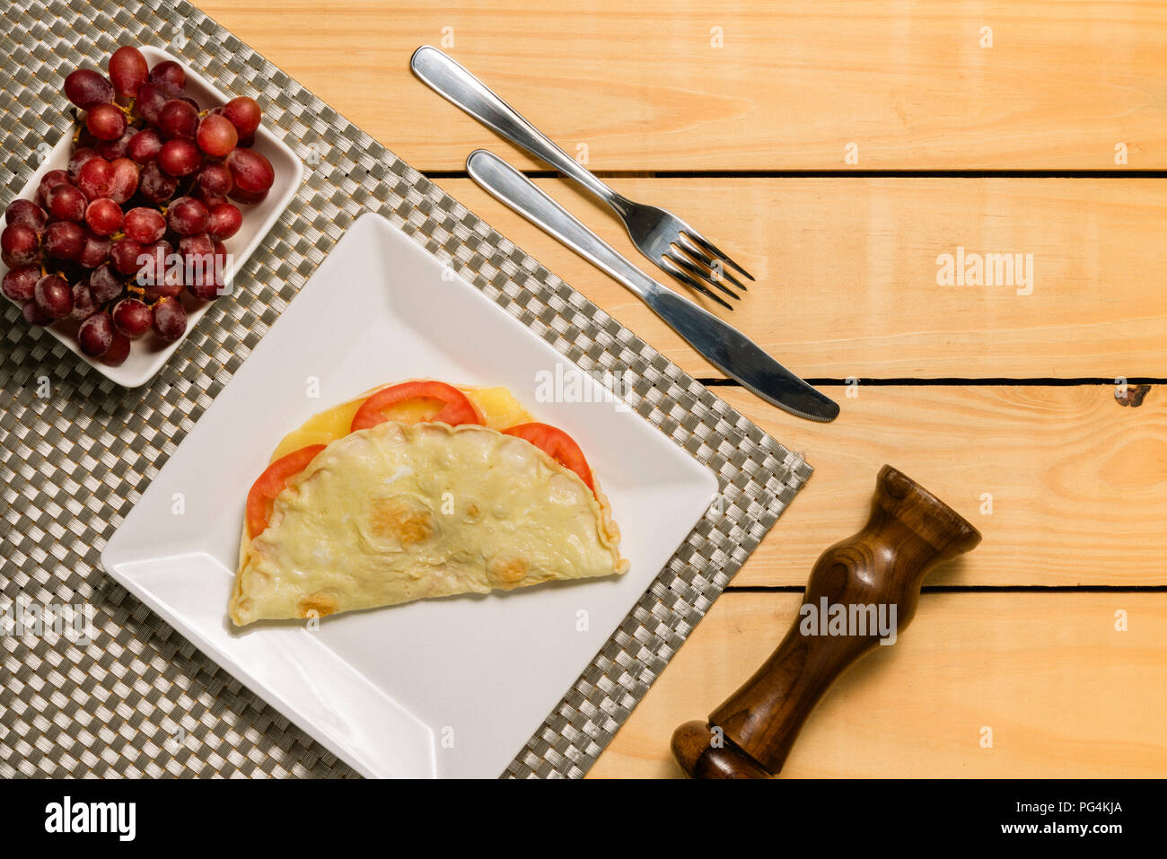 Crepioca - pancake du manioc (tapioca) avec tomates et fromage sur la plaque sur fond de bois pinus - petit déjeuner Banque D'Images