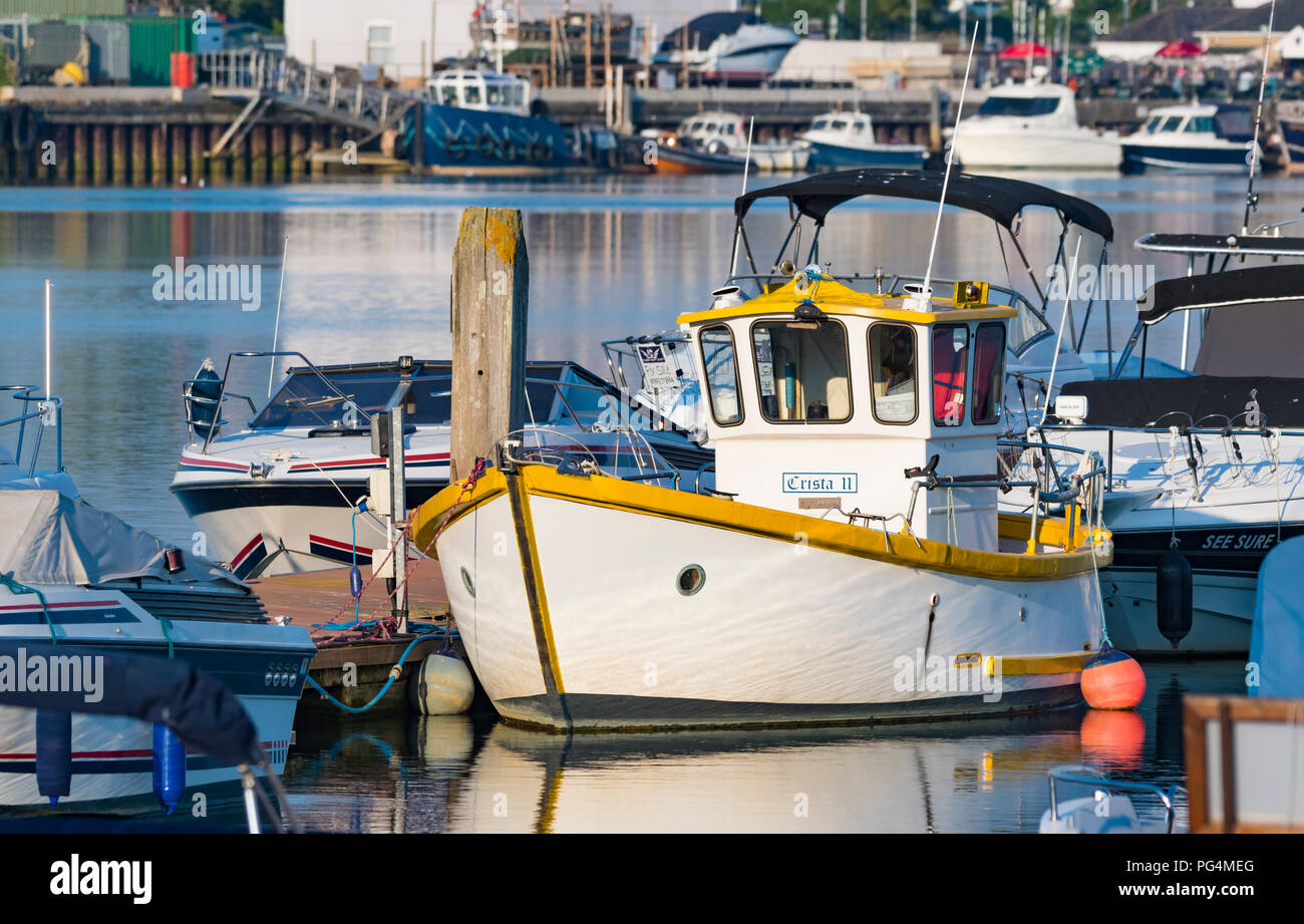 Petit bateau amarré à un ponton dans un port de plaisance sur une rivière de lumière du soir au Royaume-Uni. Banque D'Images