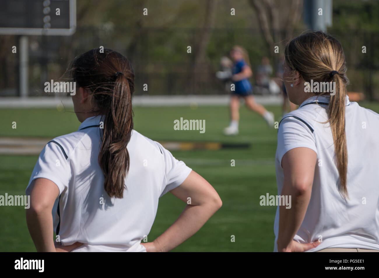Deux entraîneurs de la tête d'une femme debout sur marge appelant instructions aux joueurs de football de girl jeu de match de tournoi sur pelouse. Flou sur l'épaule Banque D'Images