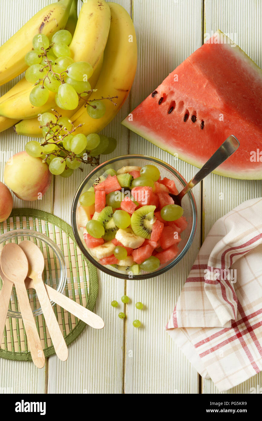 Salade de fruits d'été dans le bol en verre - pastèque, pêche, raisin, banane et kiwi - libre Banque D'Images