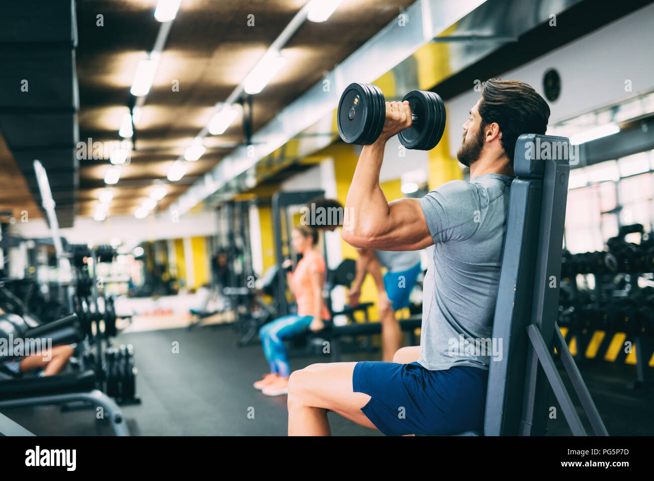 Young handsome man doing exercises in gym Banque D'Images