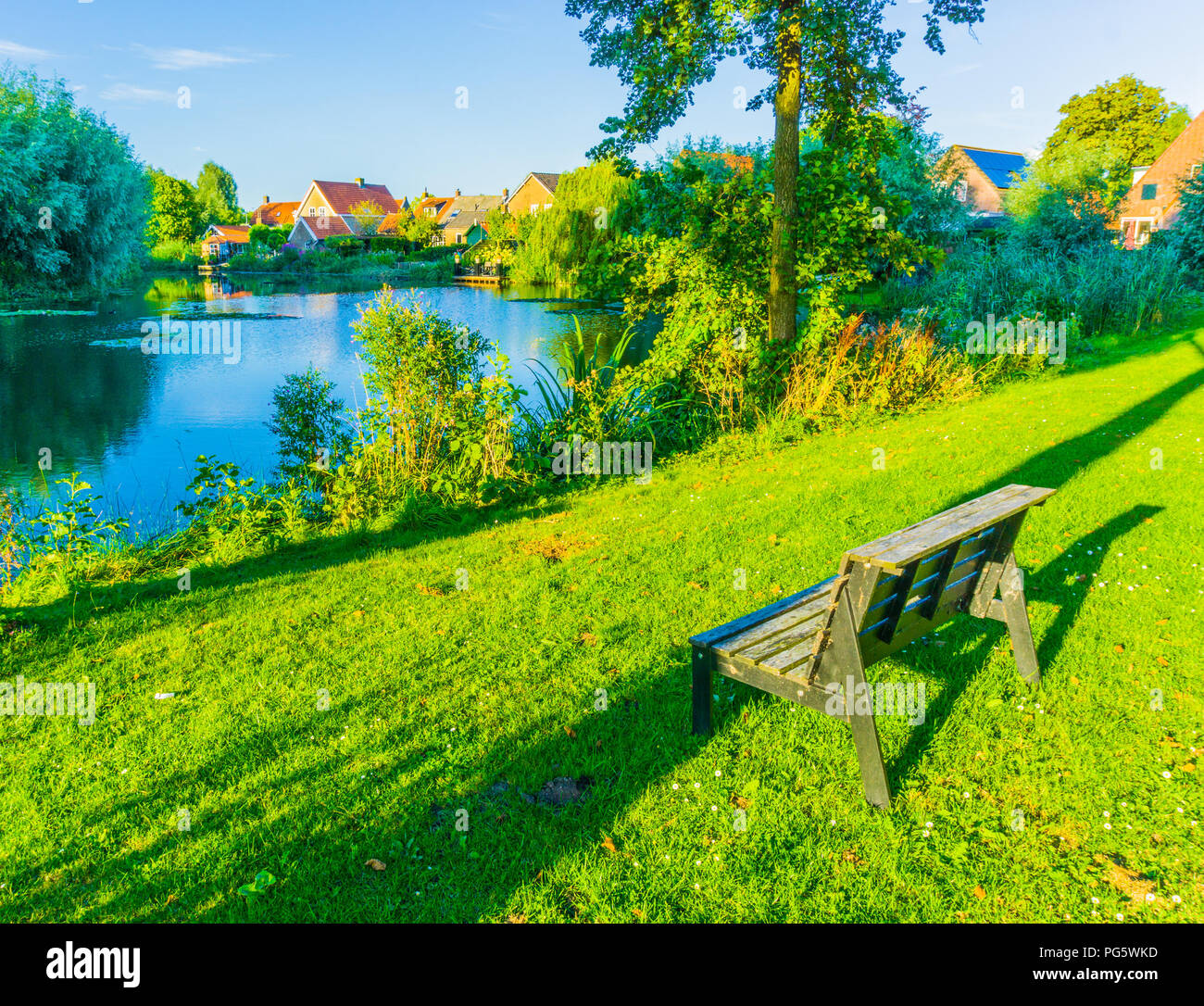 Petit banc en bois dans un beau parc avec paysage du lac Banque D'Images