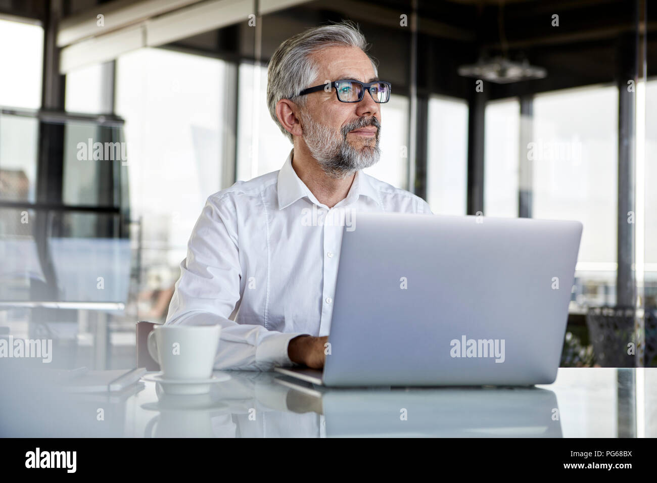 Businessman with laptop at desk in office penser Banque D'Images