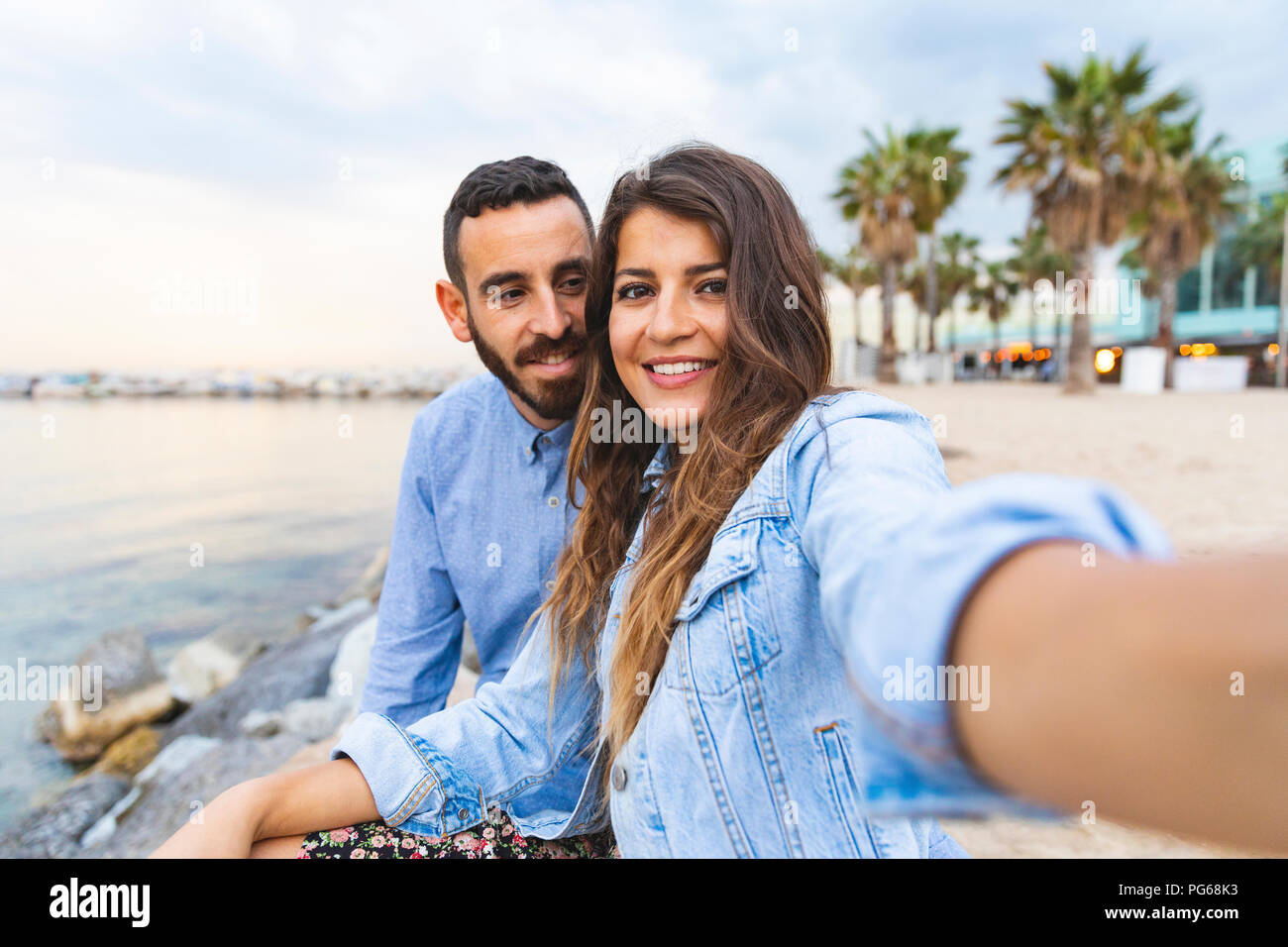 Espagne, Barcelone, smiling couple prenant une à la mer selfies Banque D'Images