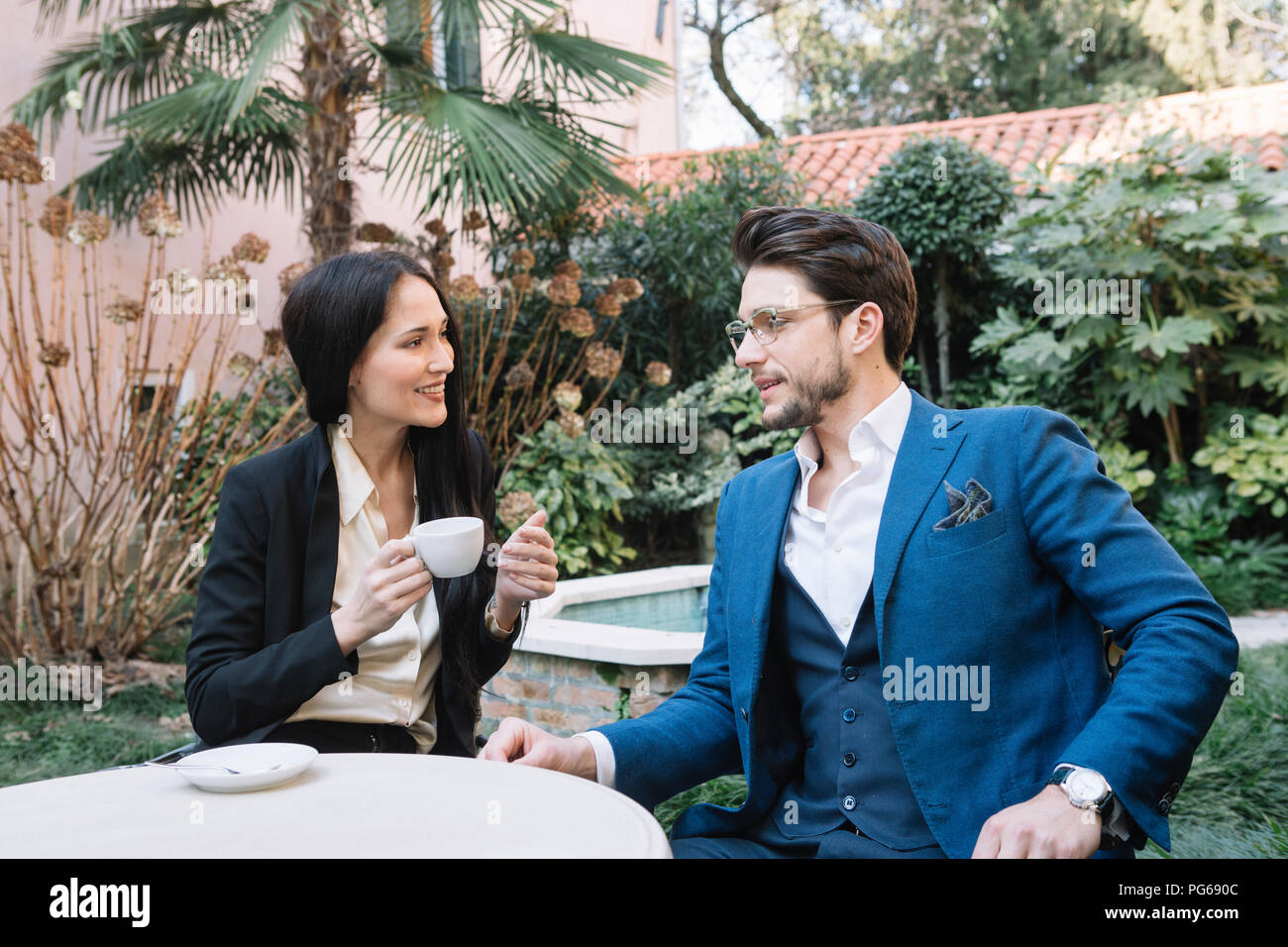 Couple élégant de parler dans un Garden Cafe Banque D'Images